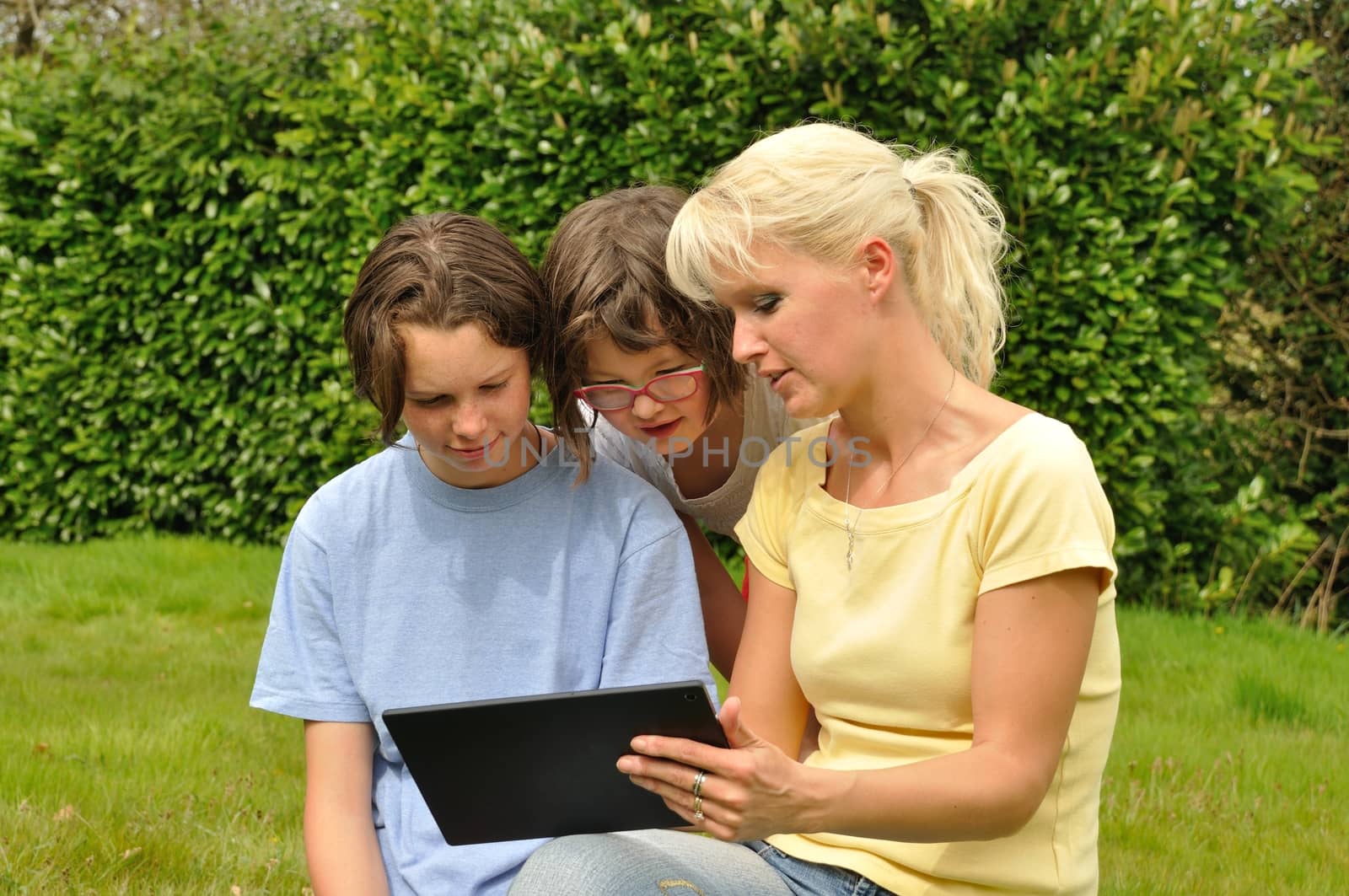 Family sitting on the lawn and using digital tablet by BZH22