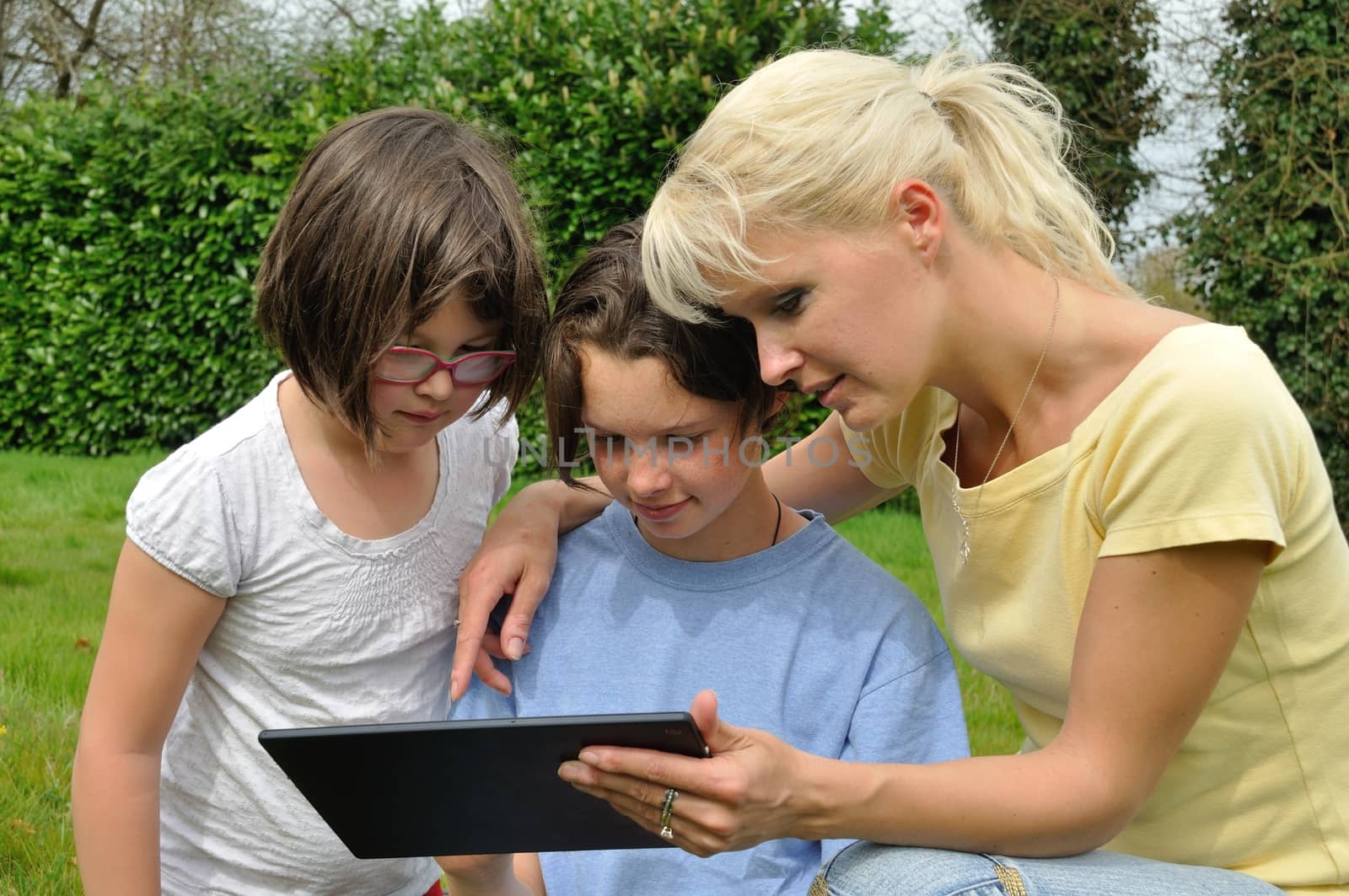 Family sitting on the lawn and using digital tablet