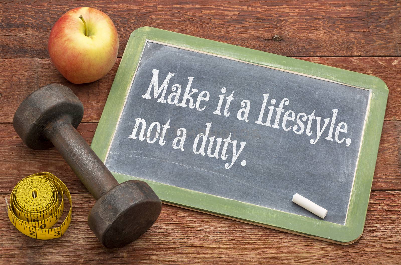 Make it a lifestyle, not a duty - fitness and healthy life concept  -  slate blackboard sign against weathered red painted barn wood with a dumbbell, apple and tape measure