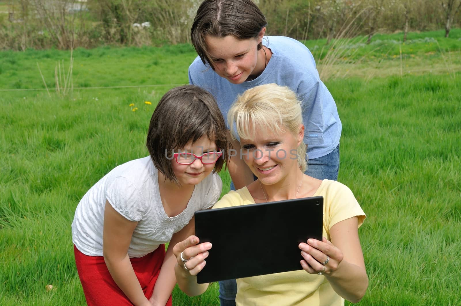 Family sitting on the lawn and using digital tablet by BZH22