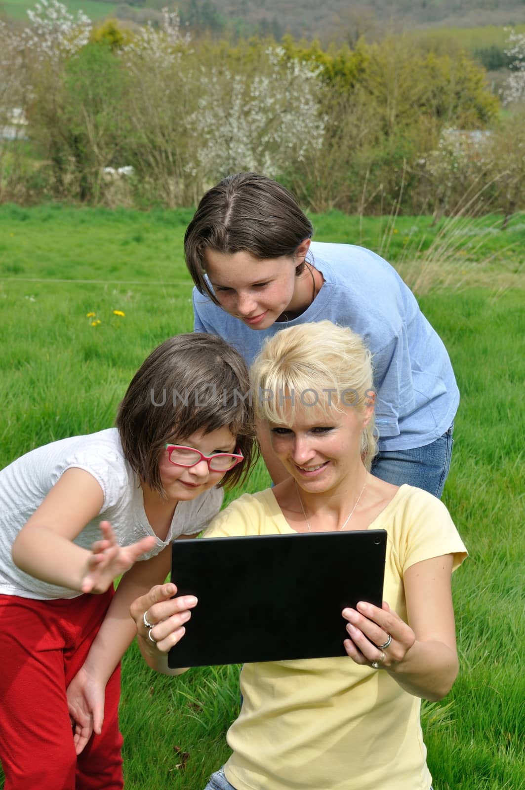 Family sitting on the lawn and using digital tablet