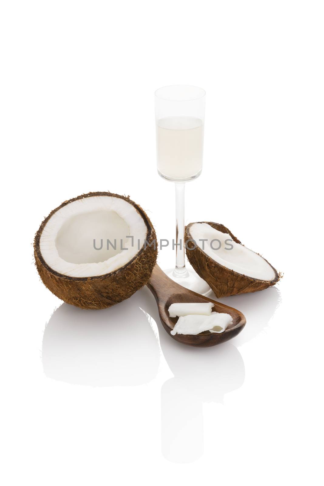 Organic liquid coconut oil in glass and wooden spoon with coconut isolated on white background. Healthy eating and cooking.