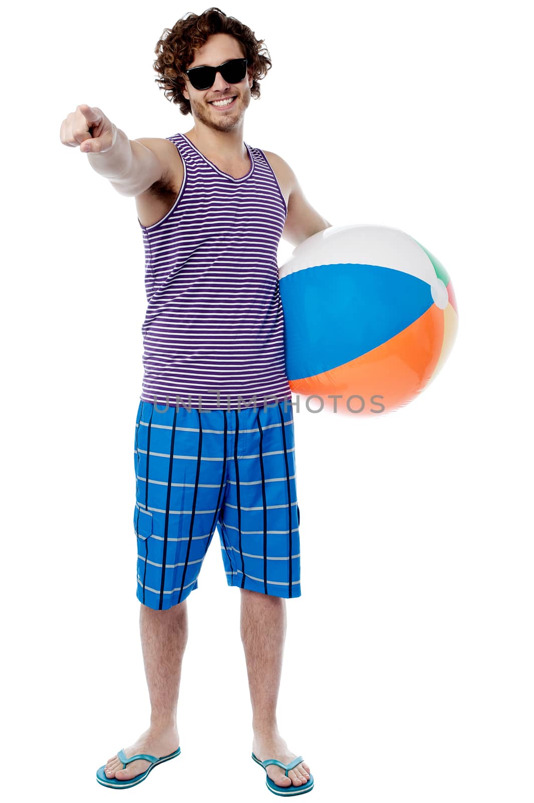 Young man with beach ball and pointing to camera