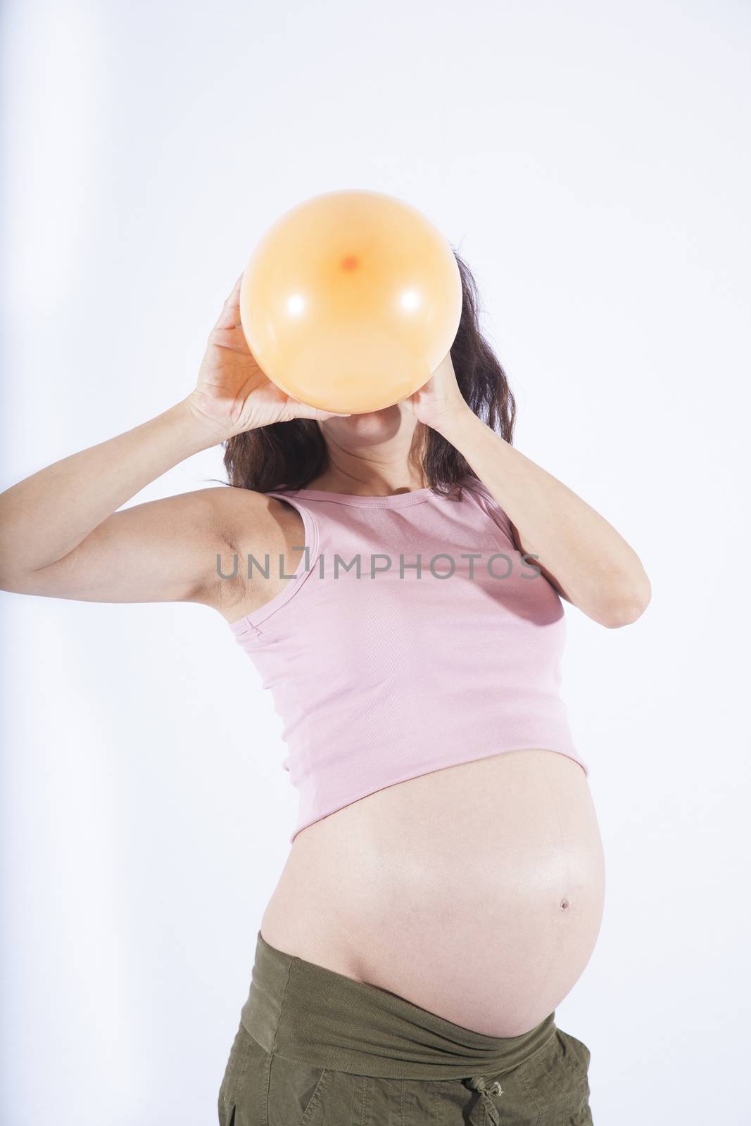 front of naked paunch eight month pregnant woman inflating orange balloon isolated on over white background