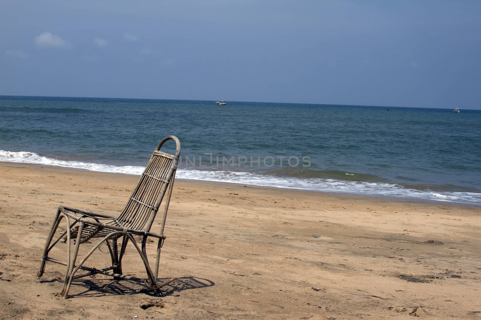 The lonely wattled chair costs on a beach, against the sea. GOA India beach.