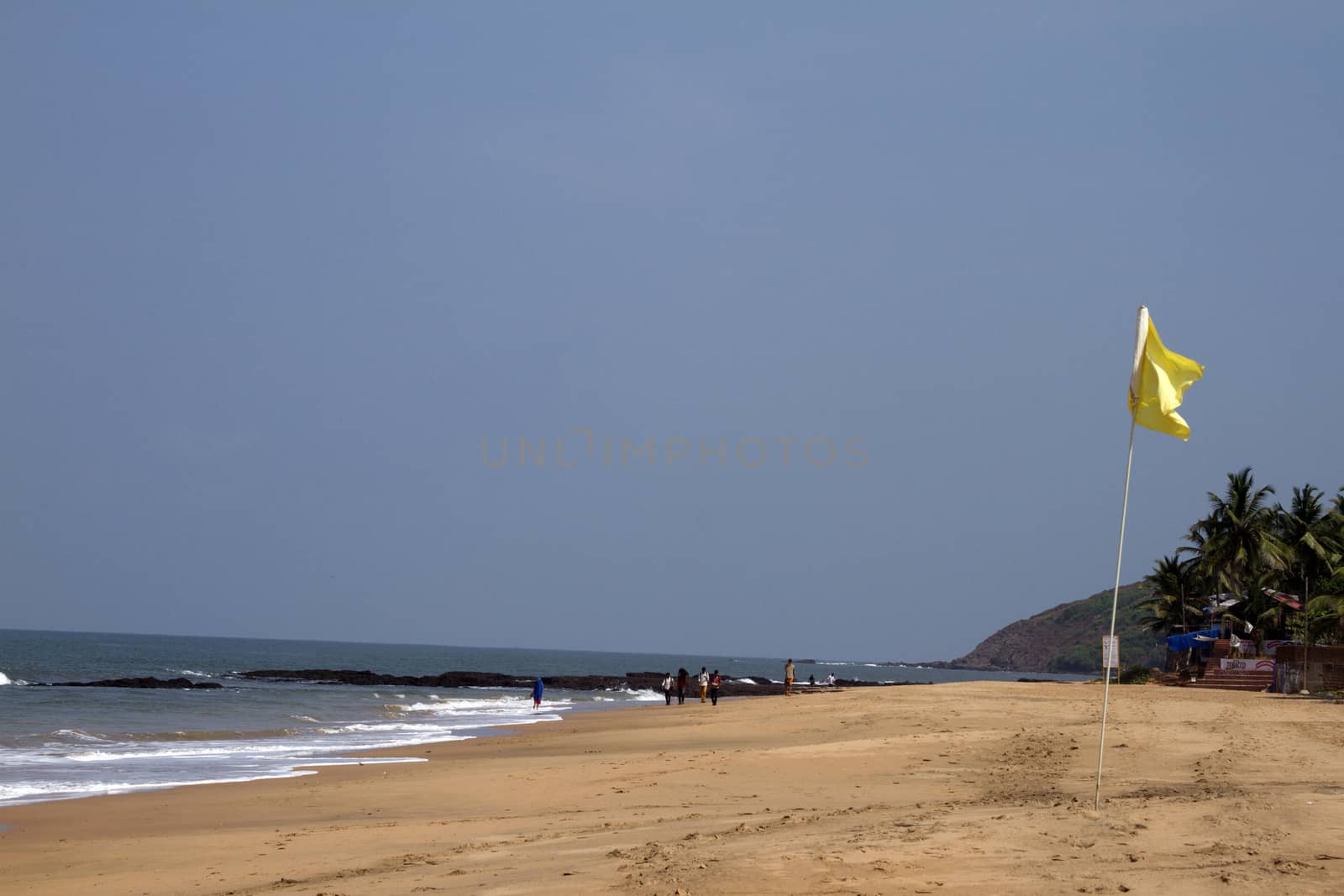 Beautiful sandy beach with a yellow flag. India Goa.