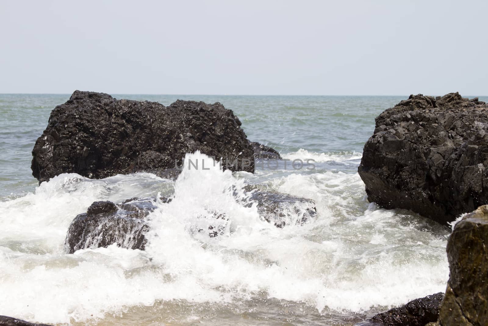 Beautiful waves of a beach of Goa, India. Wave crashing on the rocky reef by mcherevan