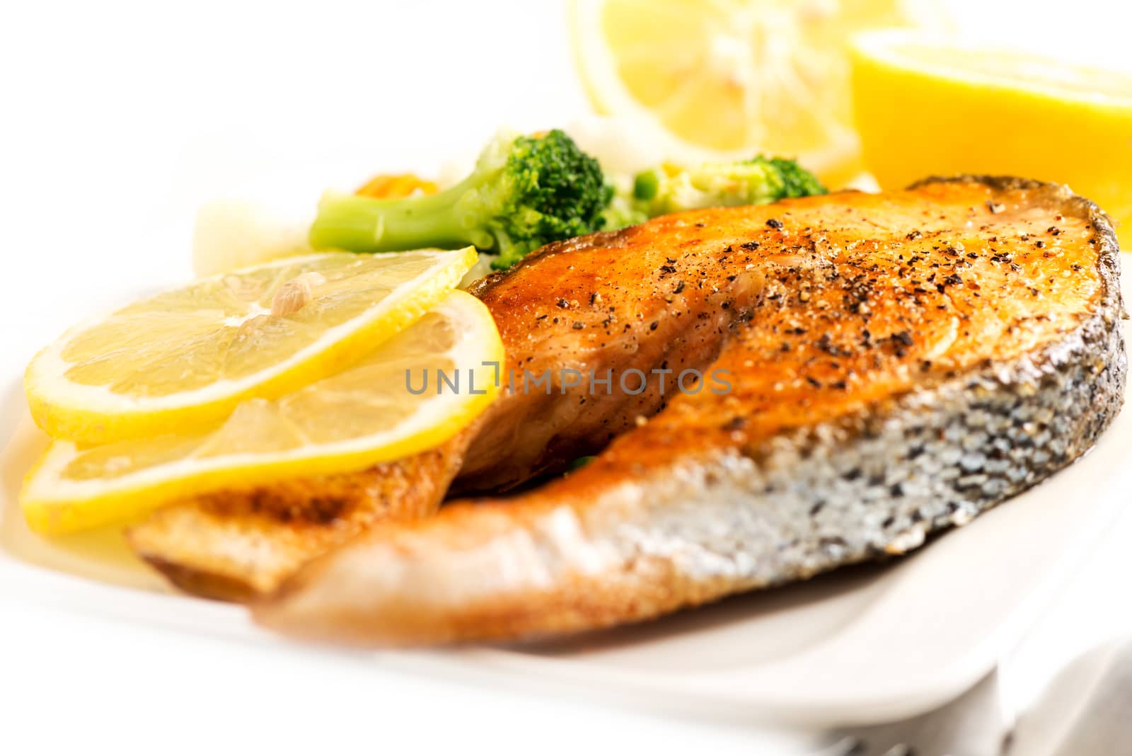 Grilled salmon and vegetables on white with selective focus by Nanisimova