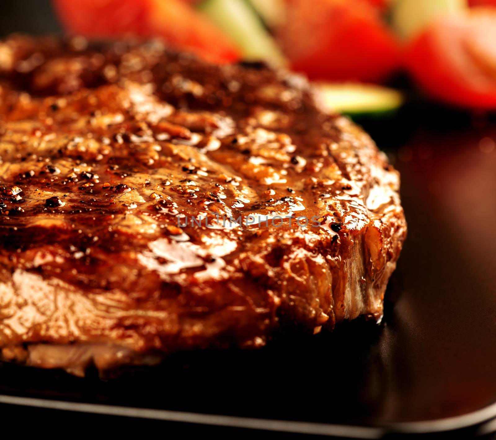 Grilled steak and vegetables on black plate close up by Nanisimova