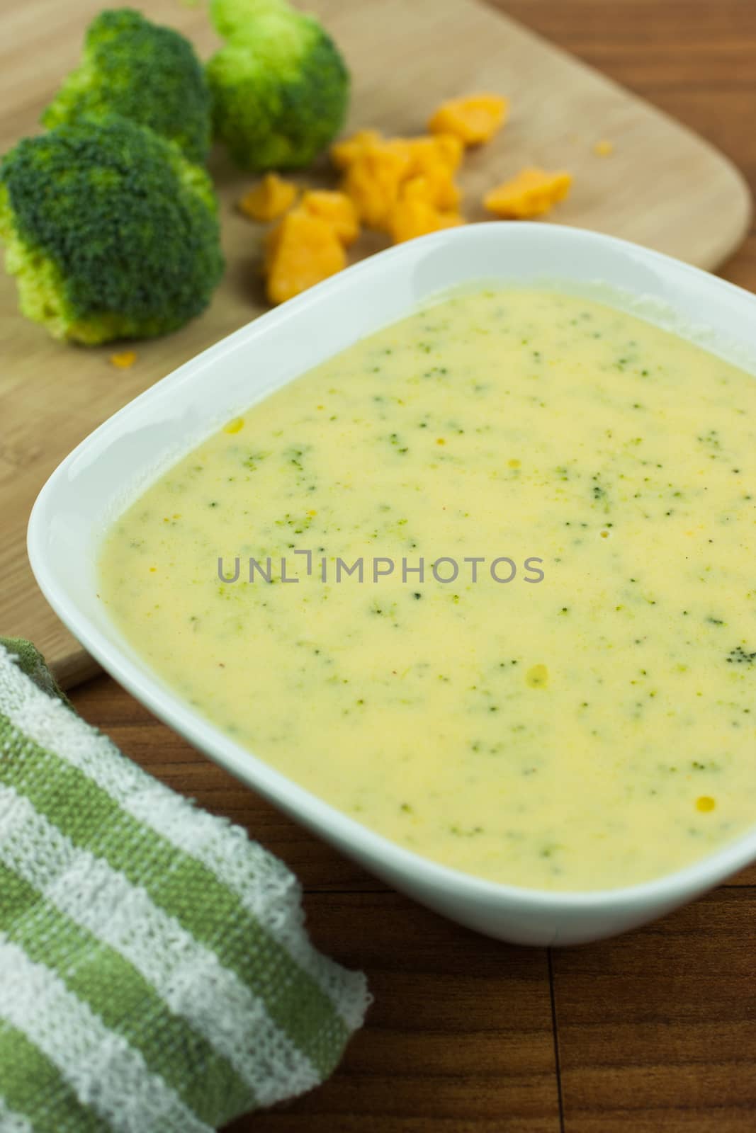 Broccoli cheese soup in a white bowl on a wooden table.