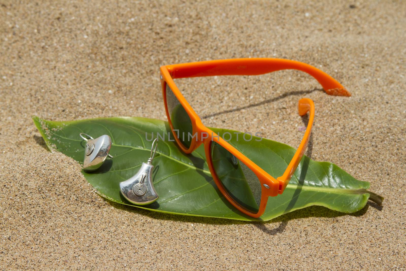 Orange sunglasses lying on the sand beach. India Goa by mcherevan