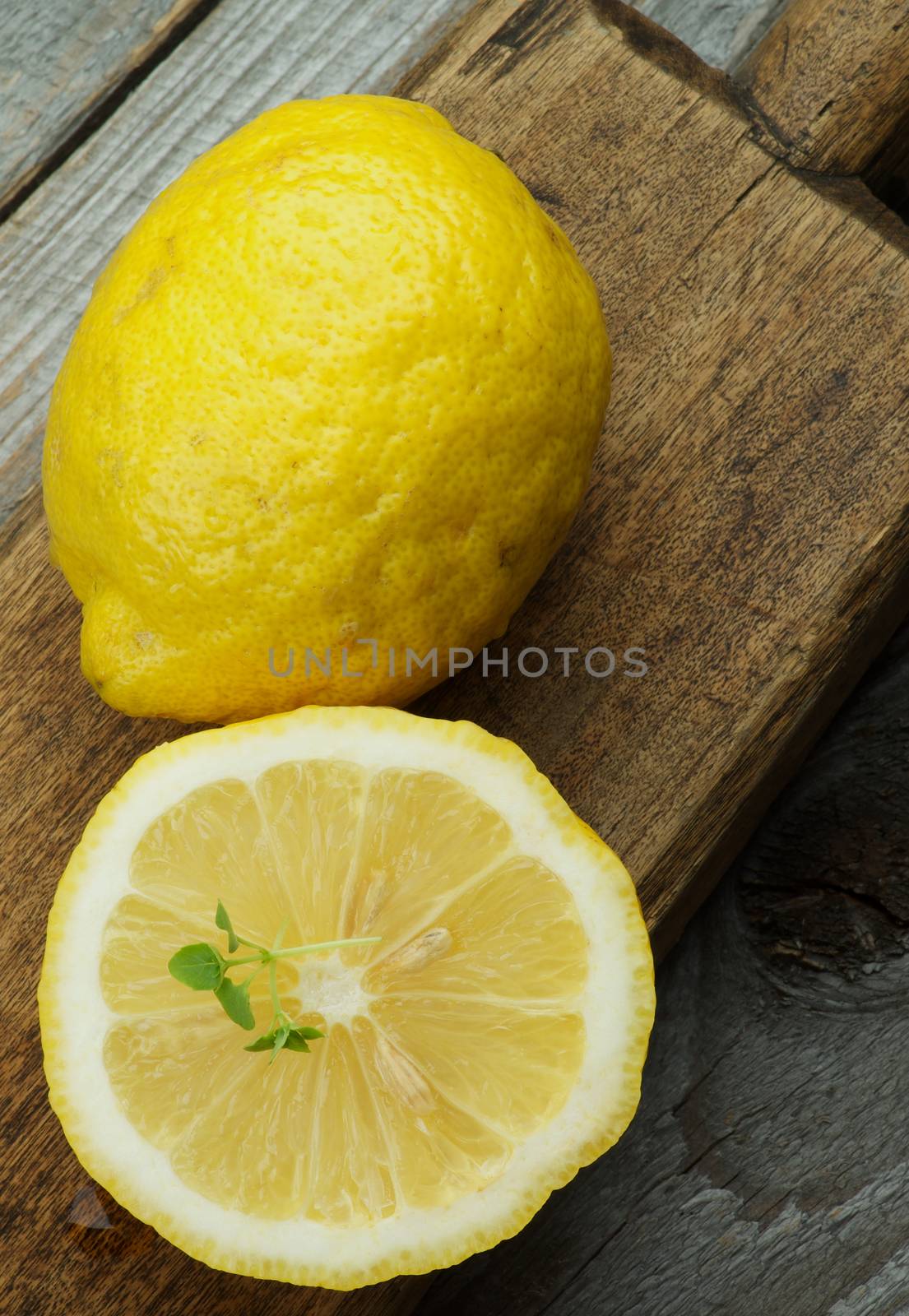 Ripe Raw Lemons Full Body and Half on Wooden Cutting Board on Rustic background