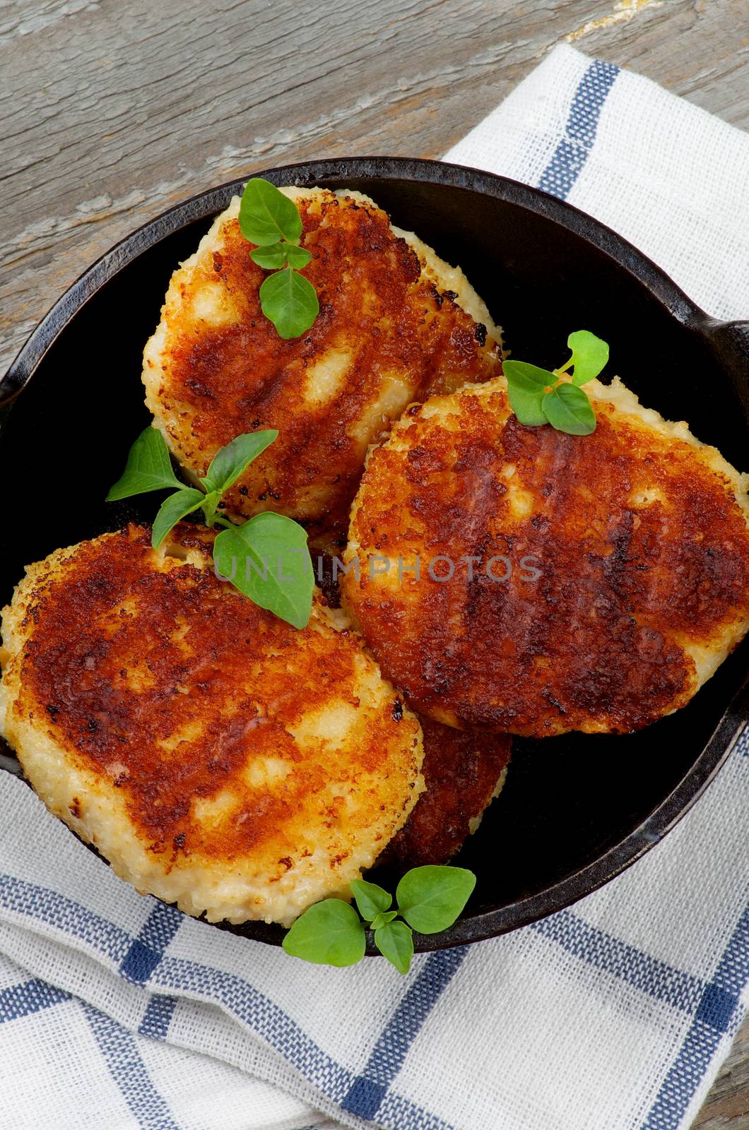 Homemade Meat Cutlets in Black Saucepan on Checkered Napkin closeup Rustic Wooden background