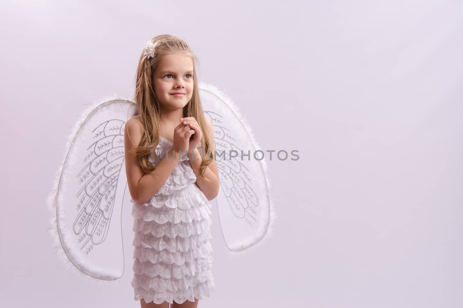 Six year old girl in a bright angel costume with wings on a white background