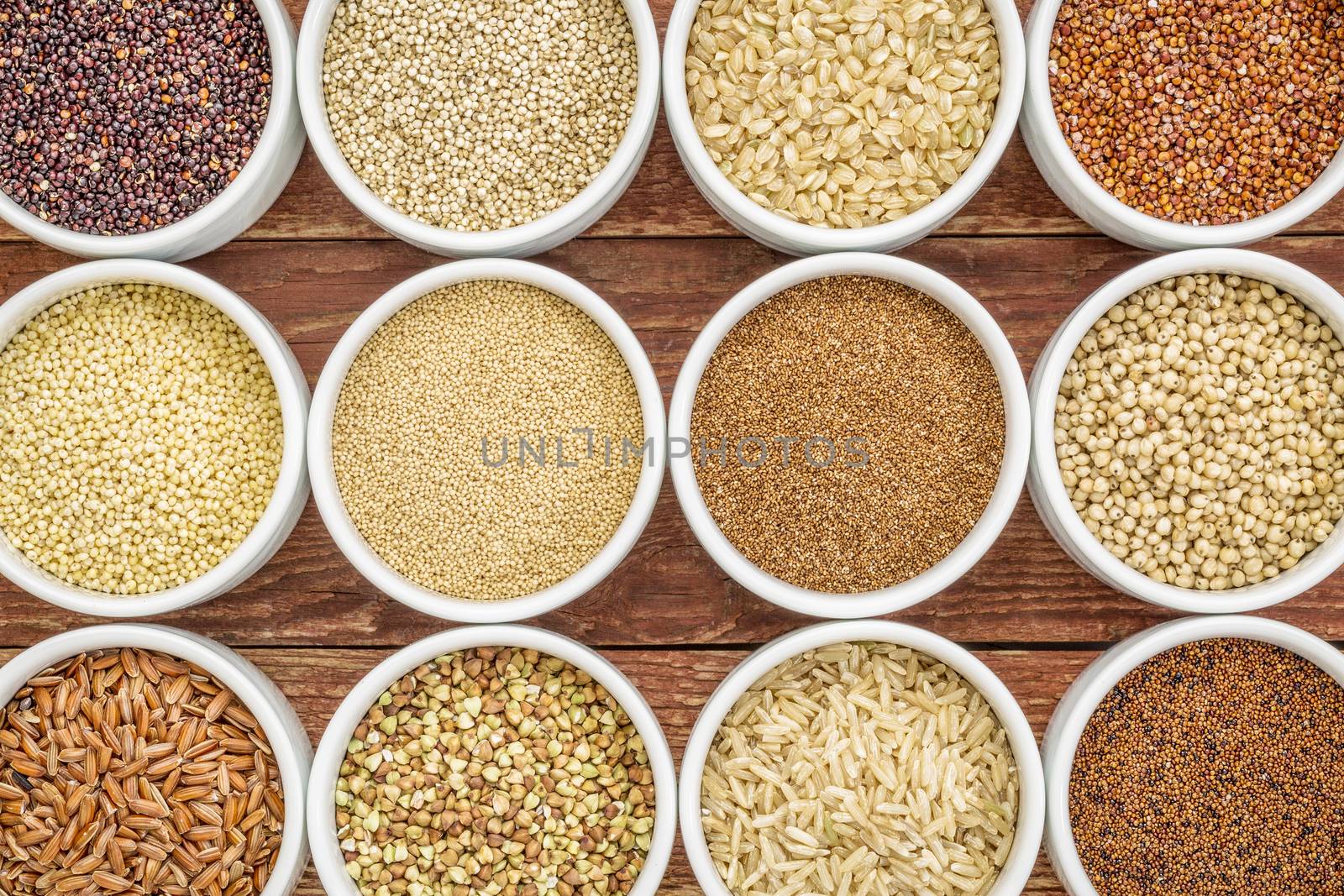 healthy, gluten free grains abstract (quinoa, brown rice, millet, amaranth, teff, buckwheat, sorghum), top view of small round bowls against rustic wood