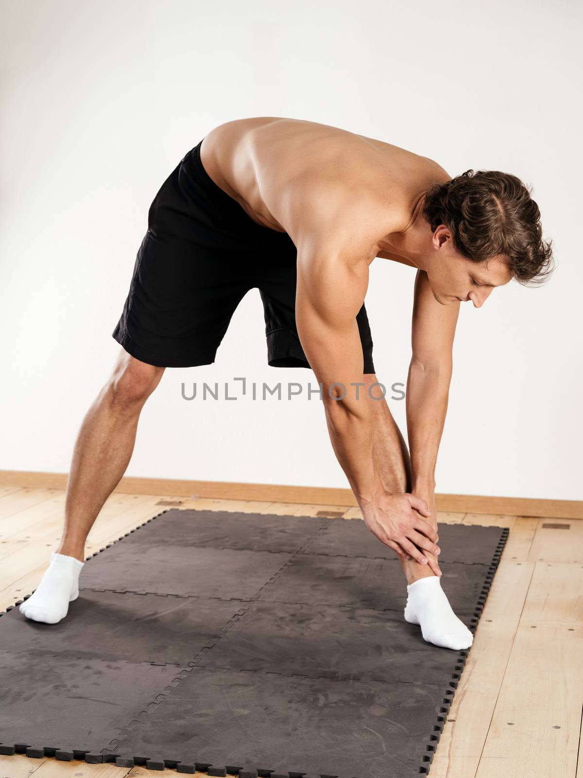 Photo of a young man stretching his legs and warming up.
