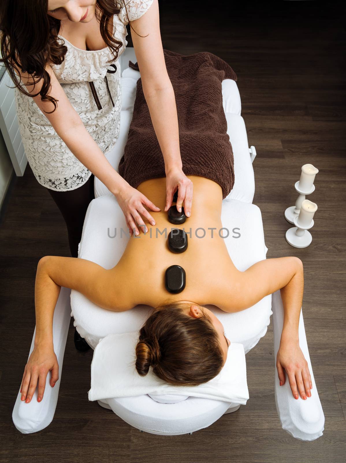 Photo of a young woman lying in a spa having a hot stone treatment. 