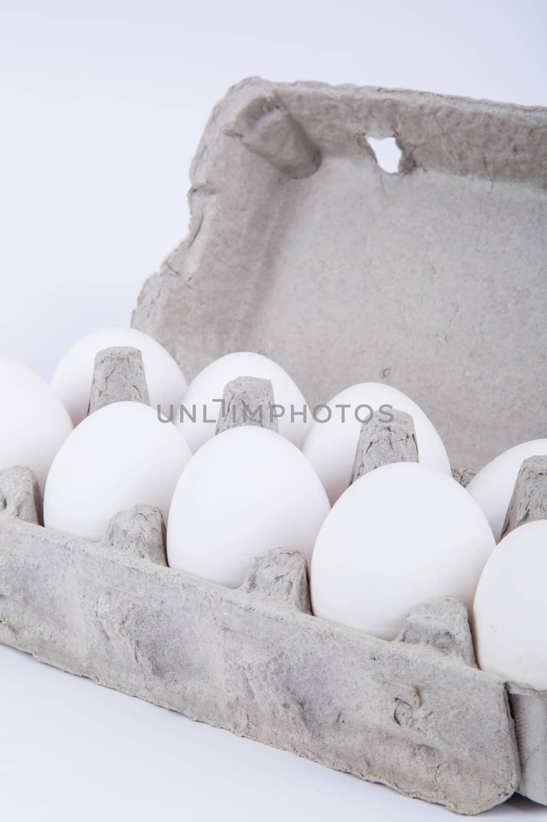 White eggs in carton with side view, isolated on white background.