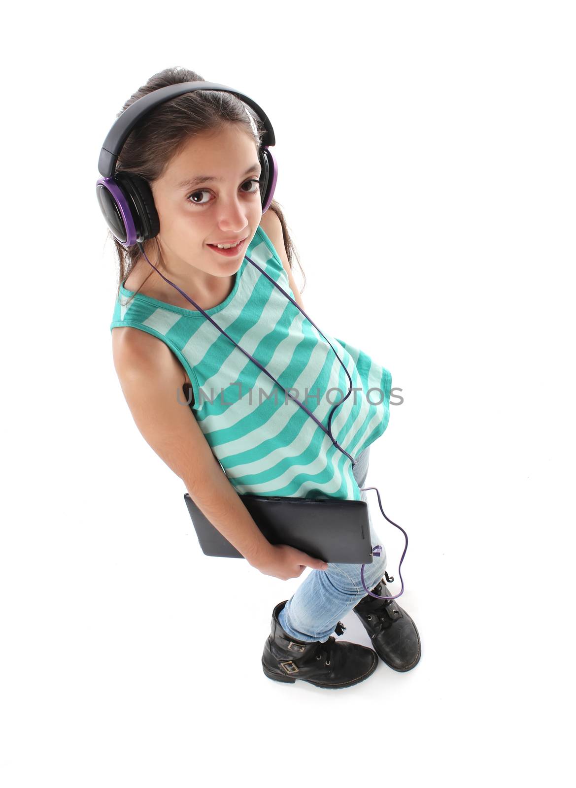 High angle picture for a beautiful pre-teen girl using a tablet computer and headphones. White background