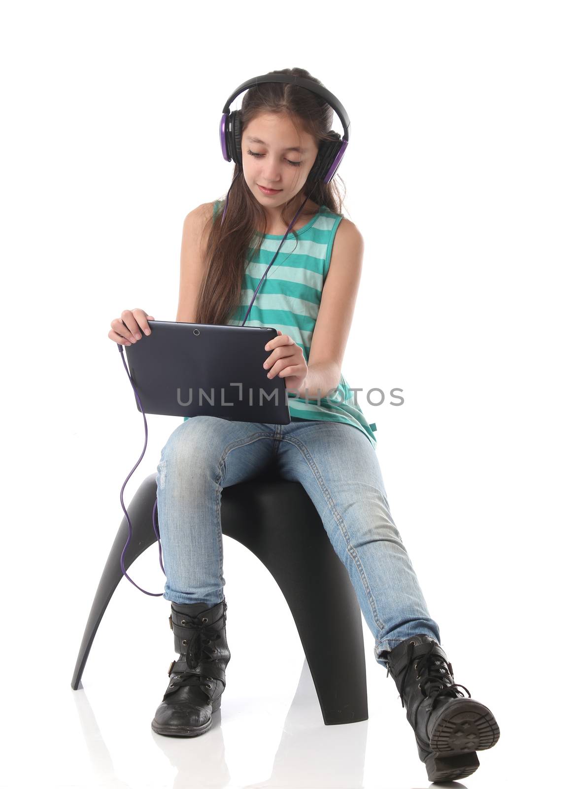 Beautiful pre-teen girl using a tablet computer and headphones.
