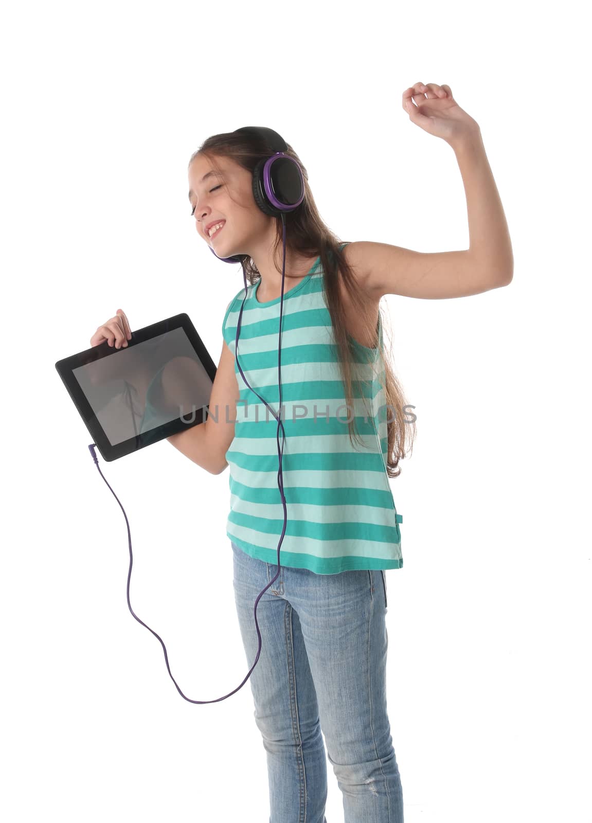 Beautiful pre-teen girl dancing with a tablet and headphones. Isolated