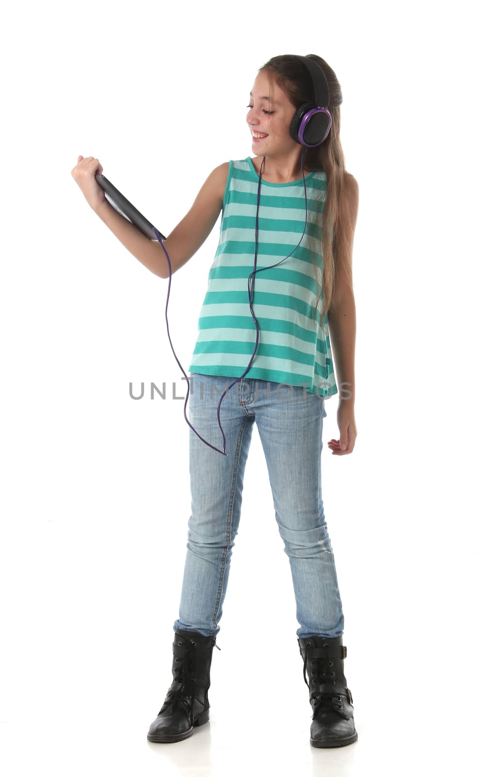 Beautiful pre-teen girl using a tablet computer and headphones. Isolated
