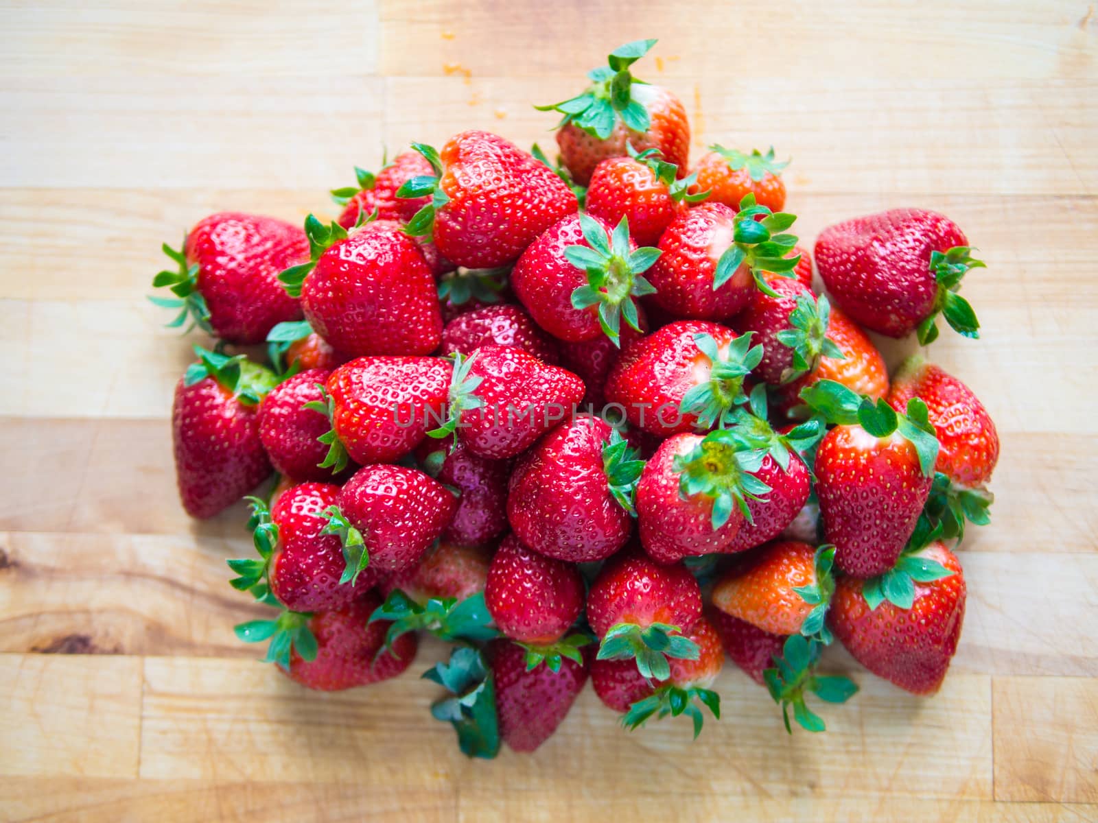 Pile of red fresh strawberries on wooden board