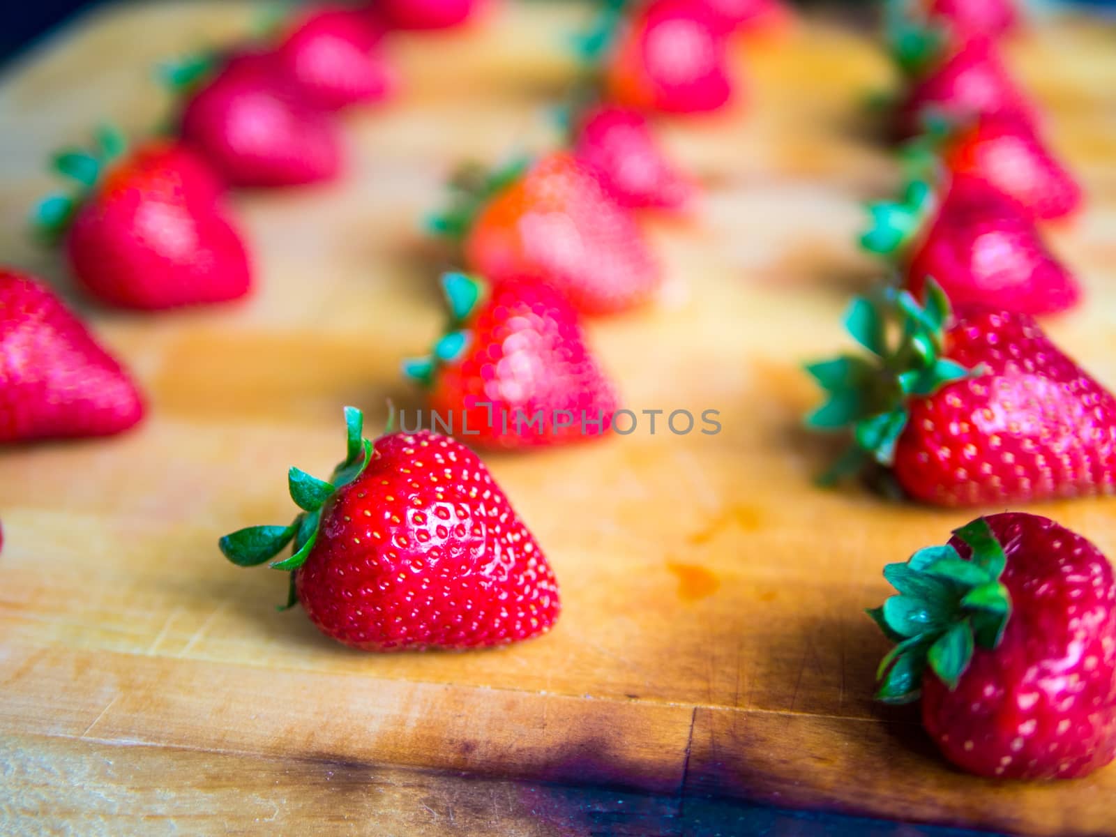 Rows of strawberries on a wooden board by weruskak