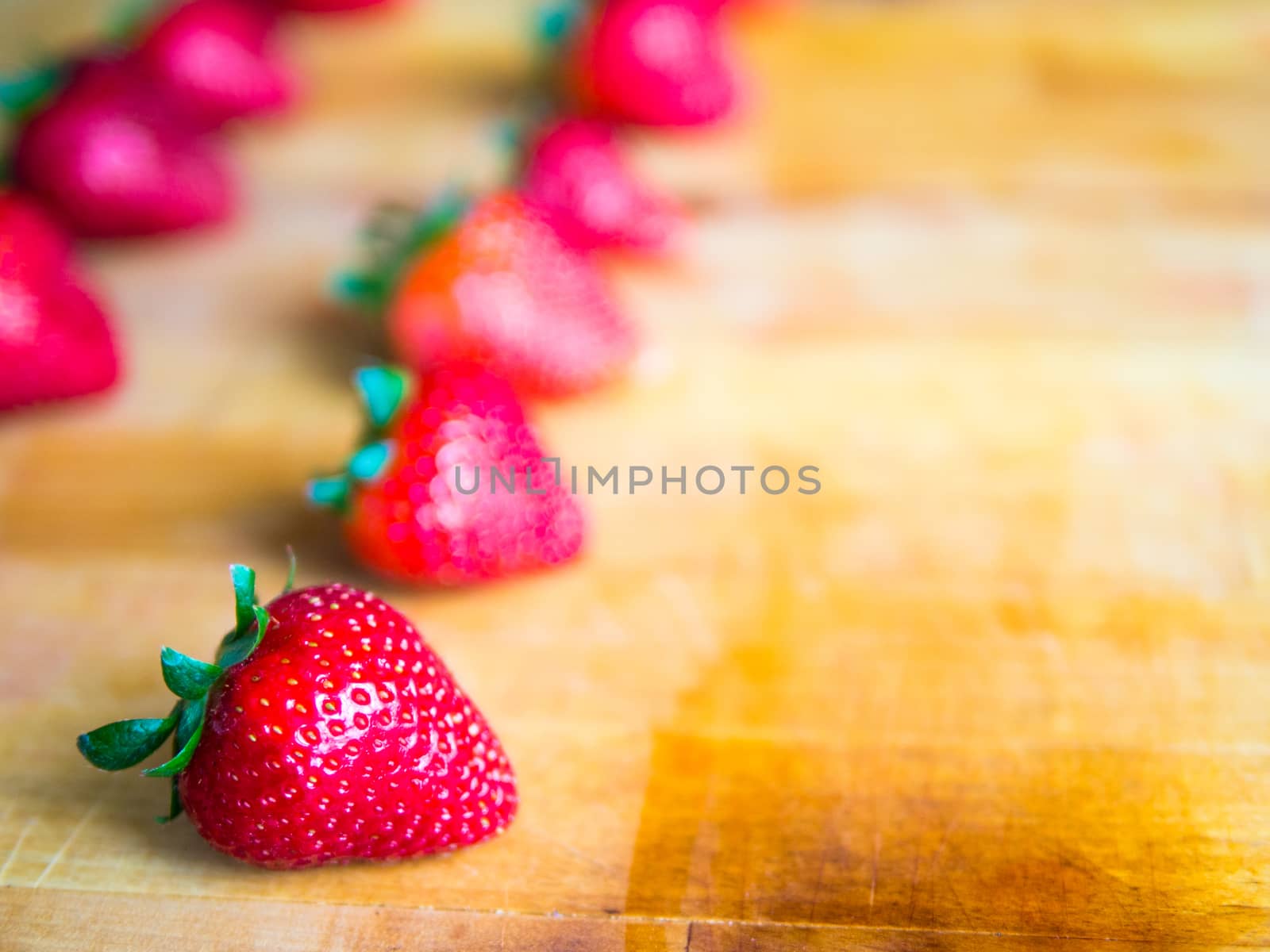 Rows of strawberries on a wooden board with empty space by weruskak