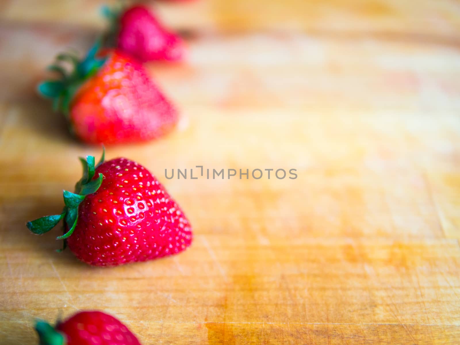 Arranged row of strawberries on a wooden board with empty space
