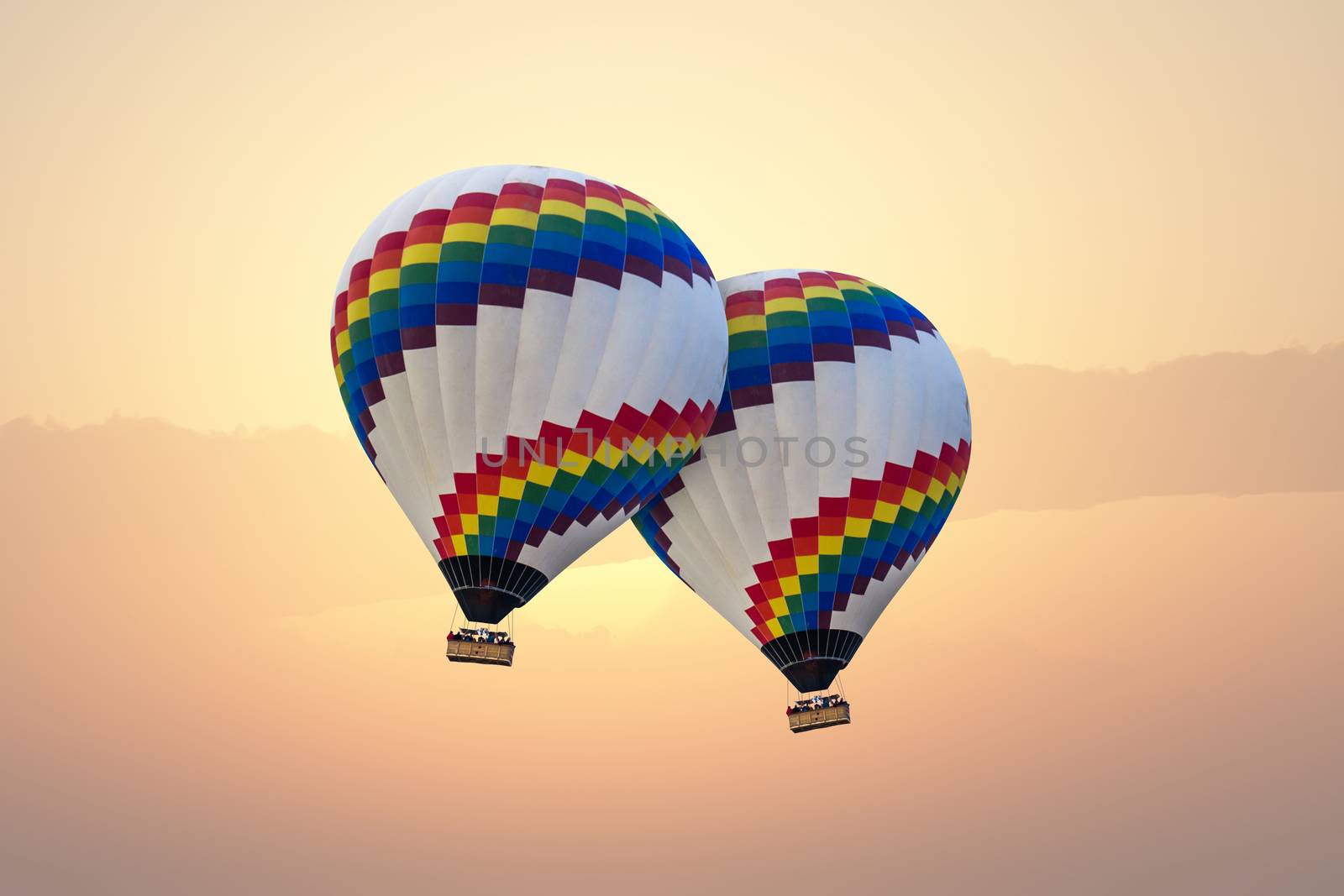 Hot air balloon flying over the sea in sunrise or sunset.