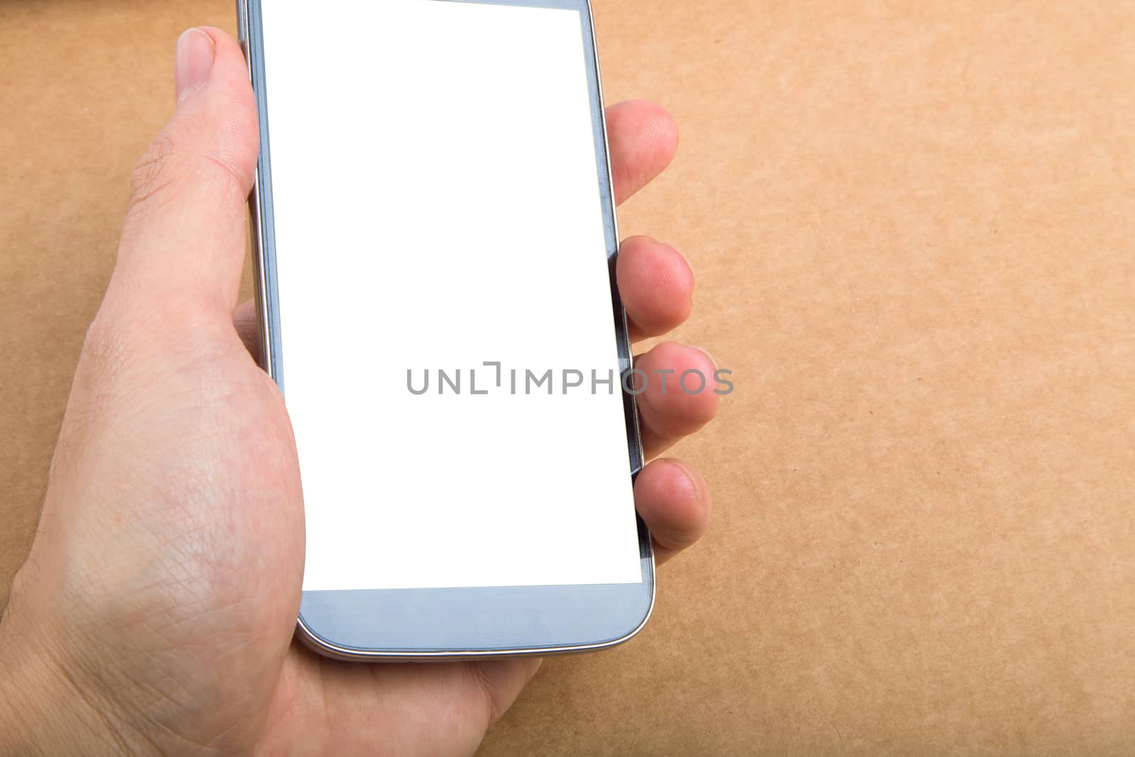 Close up view of mobile phone holding in hand with blank white screen, on wooden table.
