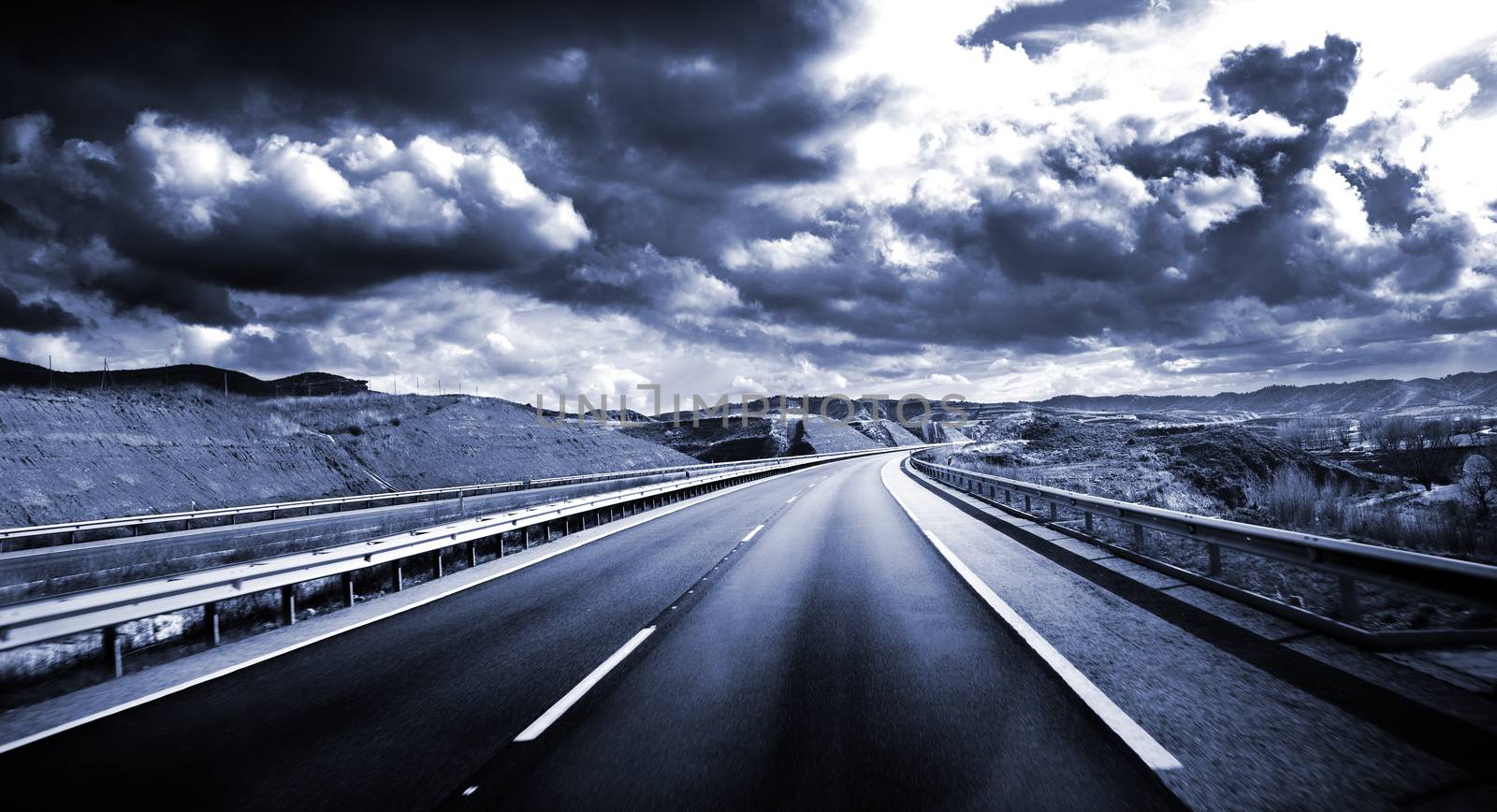 Road scenery. Travel concept.Cloudy sky and high road in blue toned
