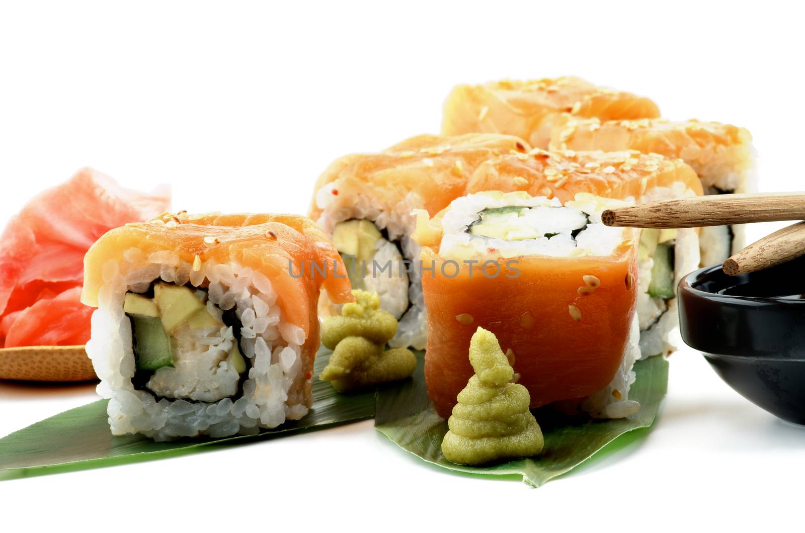 Maki Sushi with Salmon, Crab, Avocado and Cheese on Green Palm Leafs with Wasabi, Ginger and Pair of Chopsticks closeup on White background