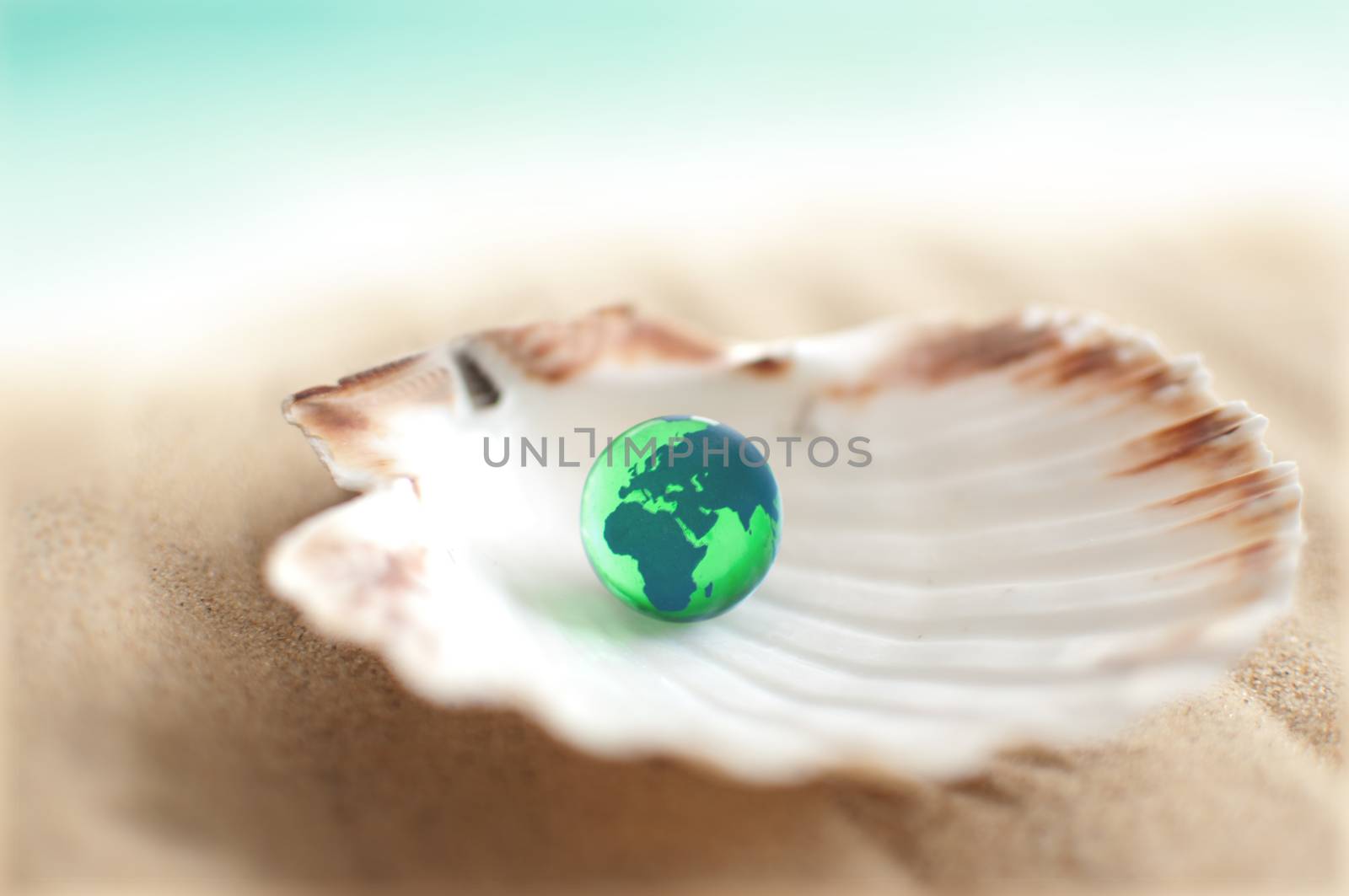 Sea shell on sand with earth globe inside 
