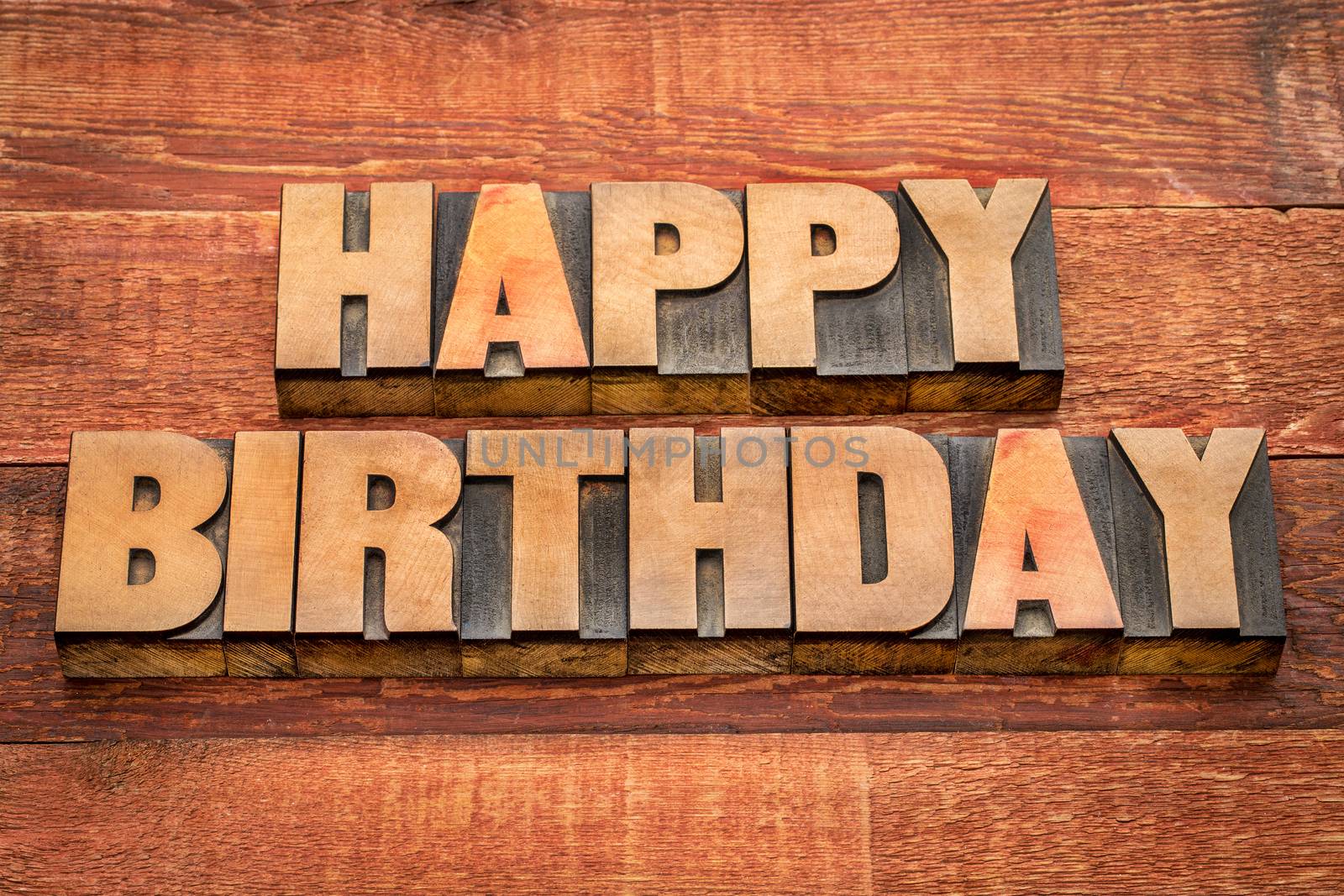 Happy Birthday greetings in letterpress wood type against rustic, red painted barn wood