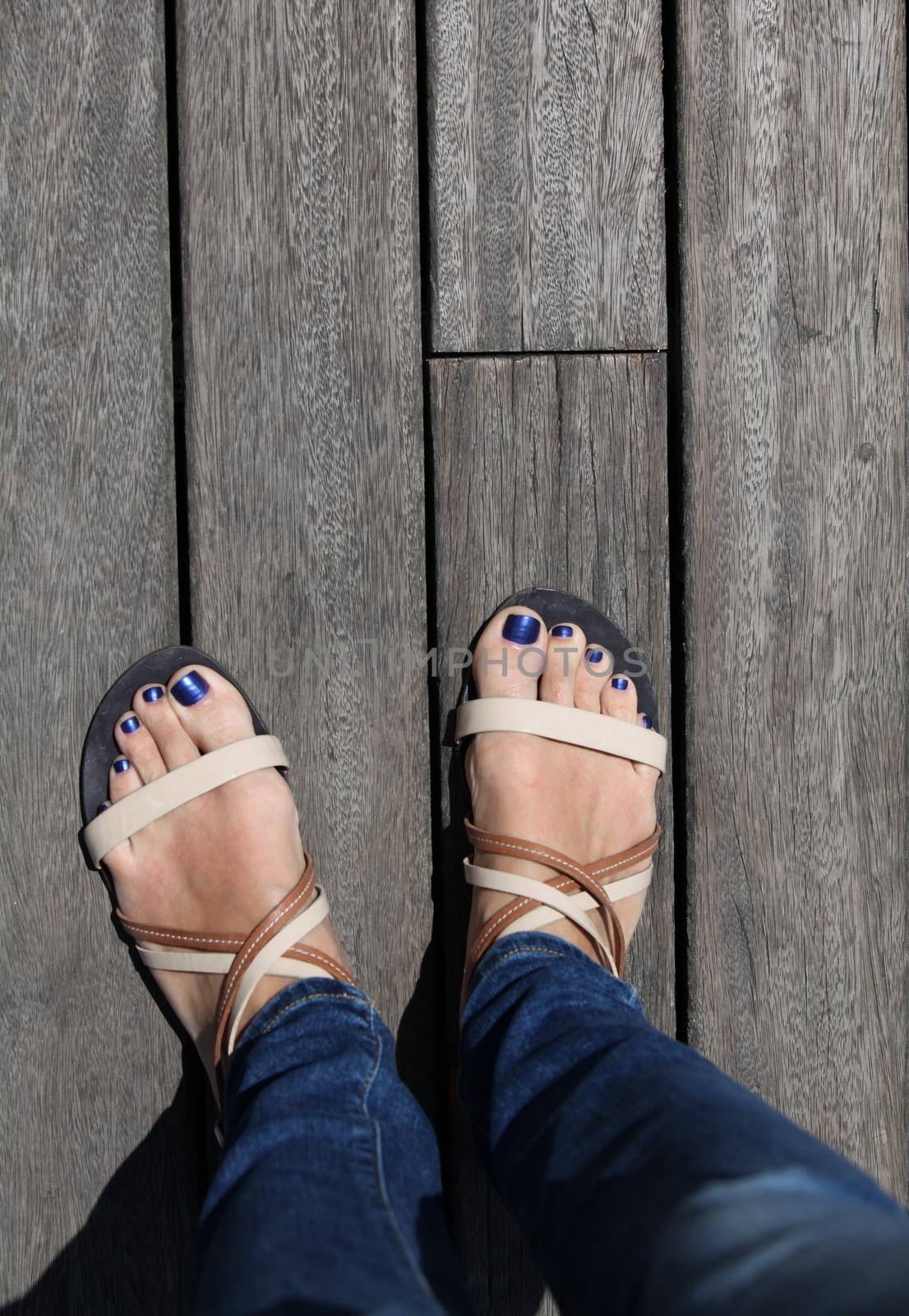 Female feet in sandals on floor background