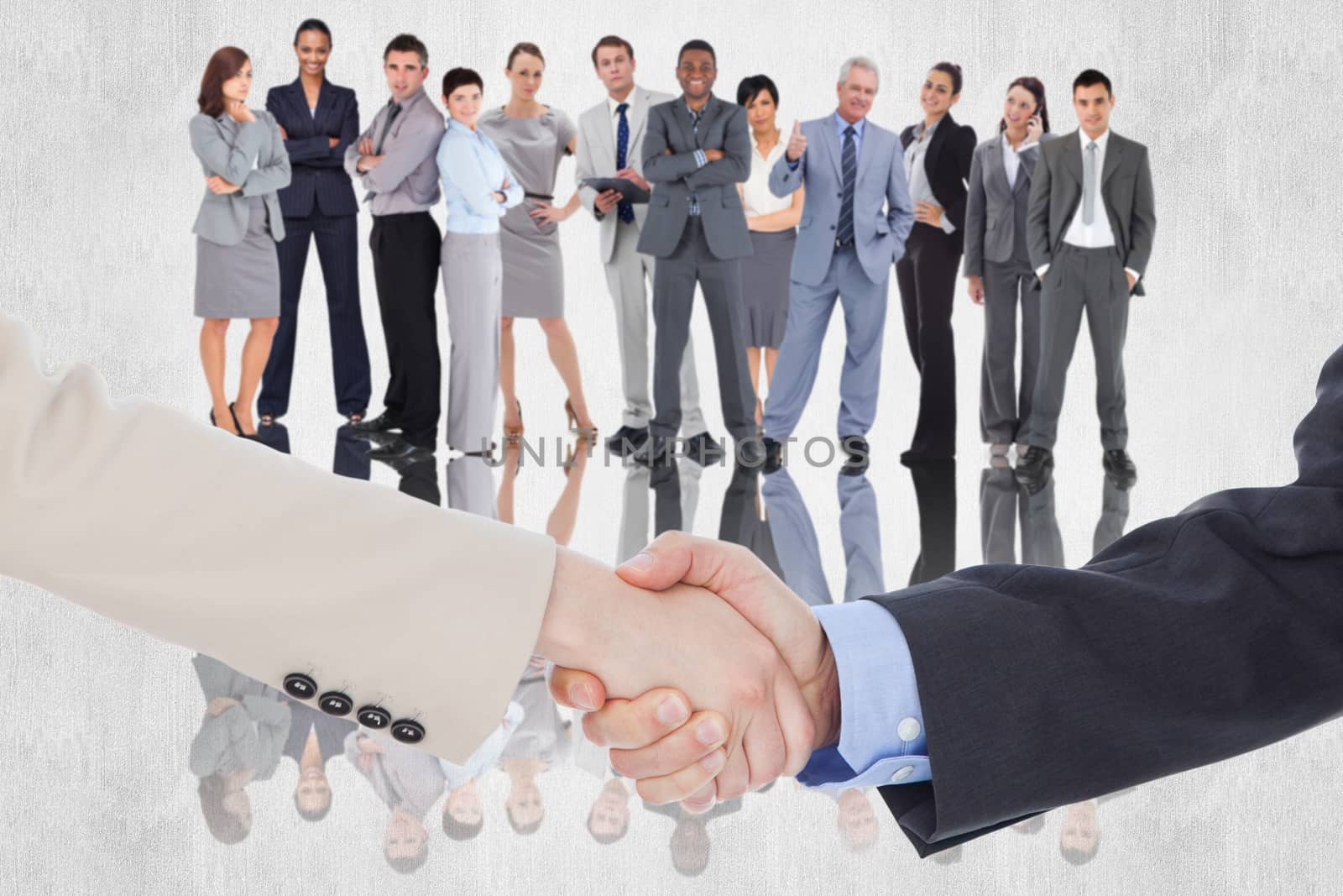 Smiling business people shaking hands while looking at the camera against white background
