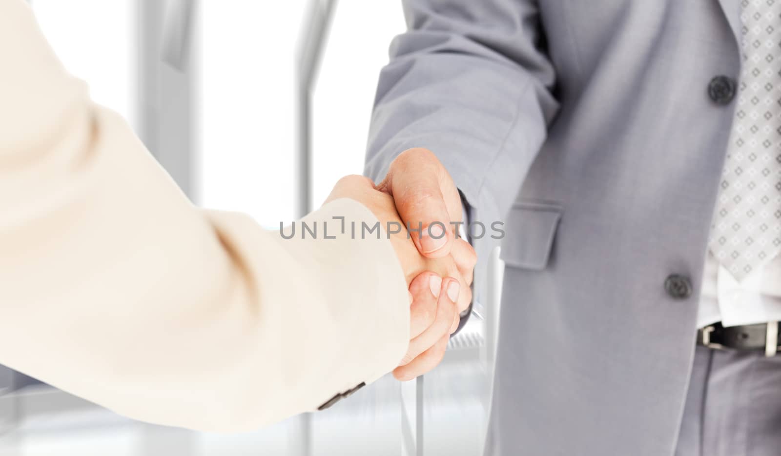 People in suit shaking hands against room with large window looking on city