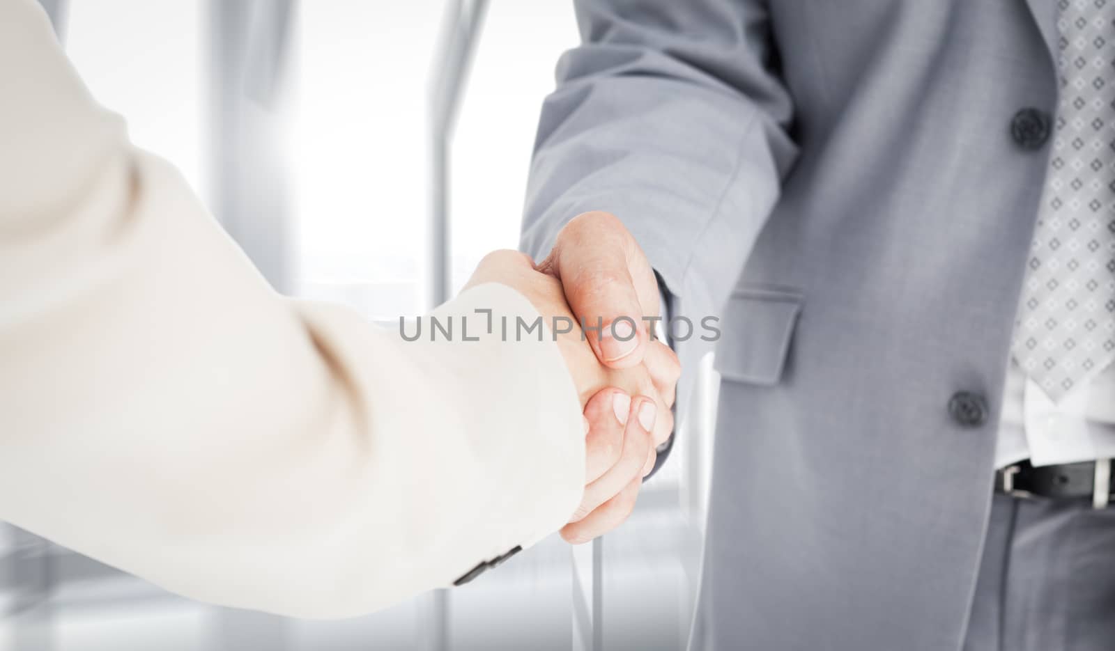 People in suit shaking hands against room with large window looking on city