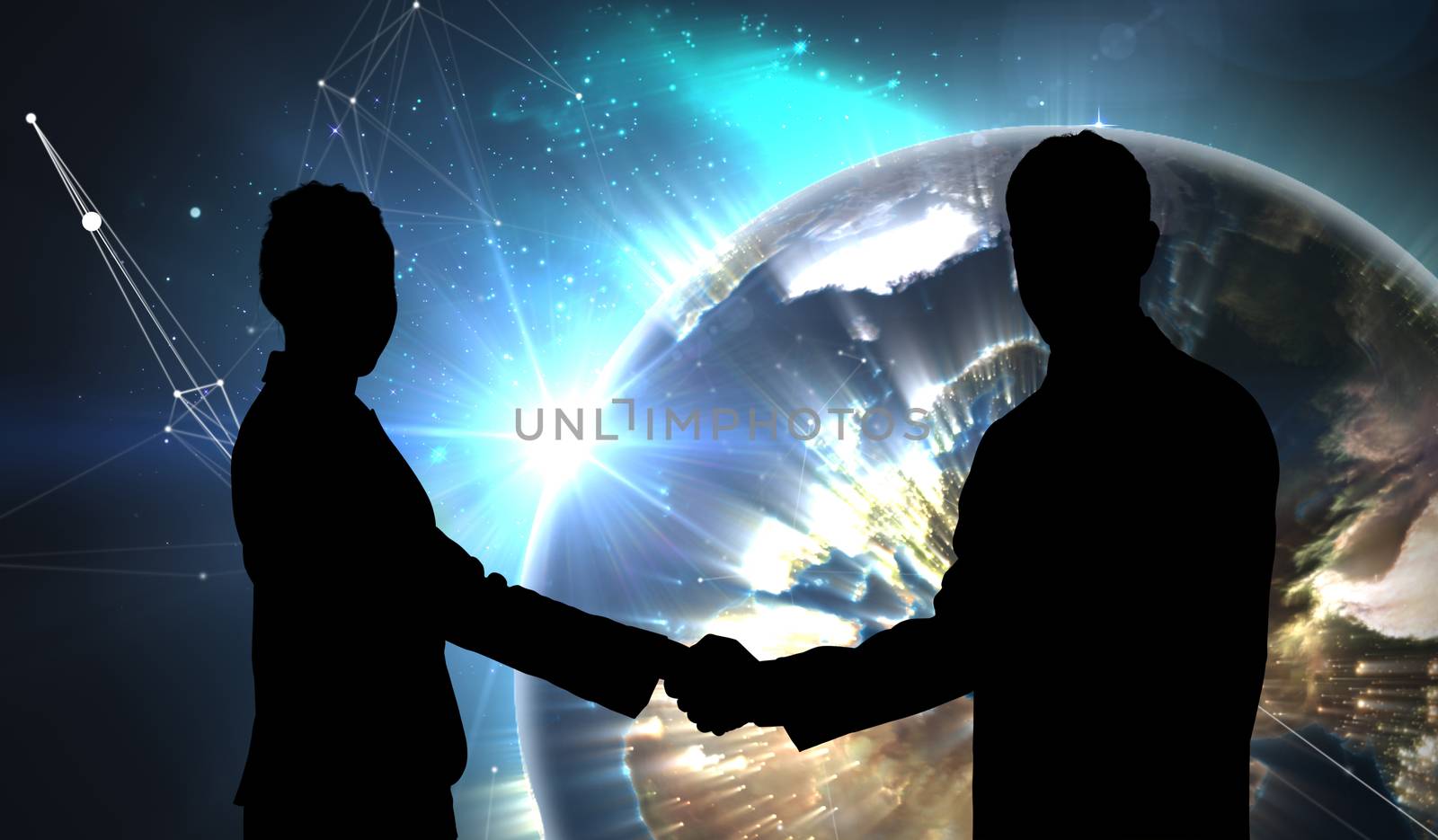 Smiling business people shaking hands while looking at the camera against earth seen from space