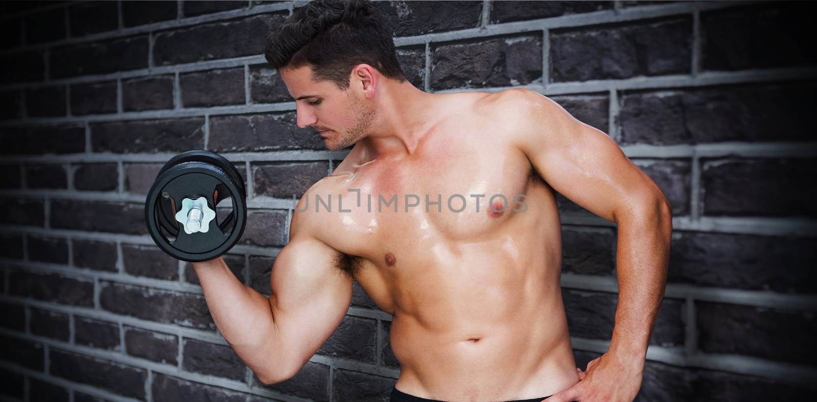 Bodybuilder lifting dumbbell against red brick wall