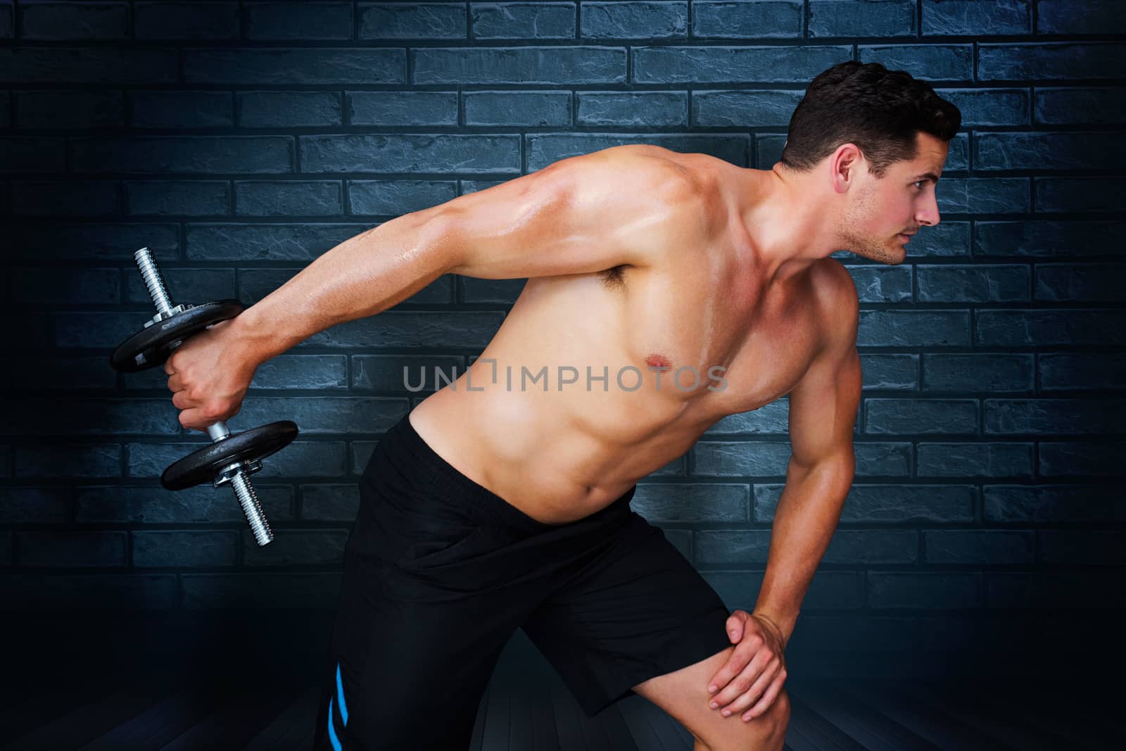 Bodybuilder lifting dumbbell against black background