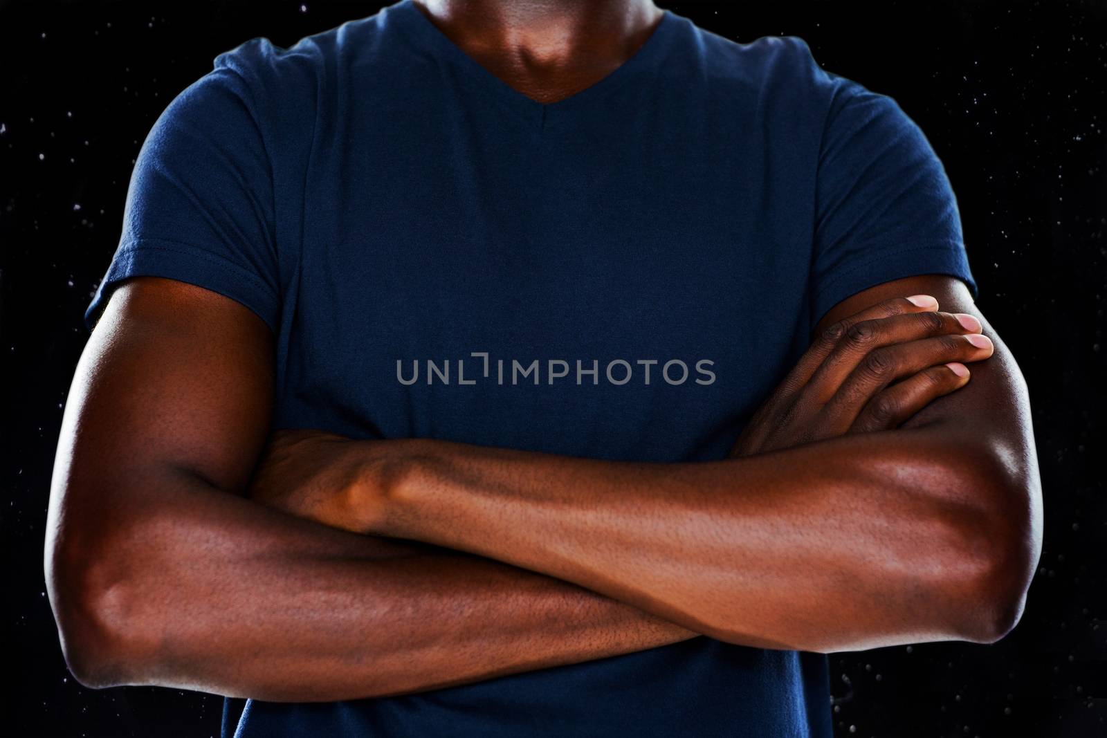 Close up mid section of man with arms crossed against black background