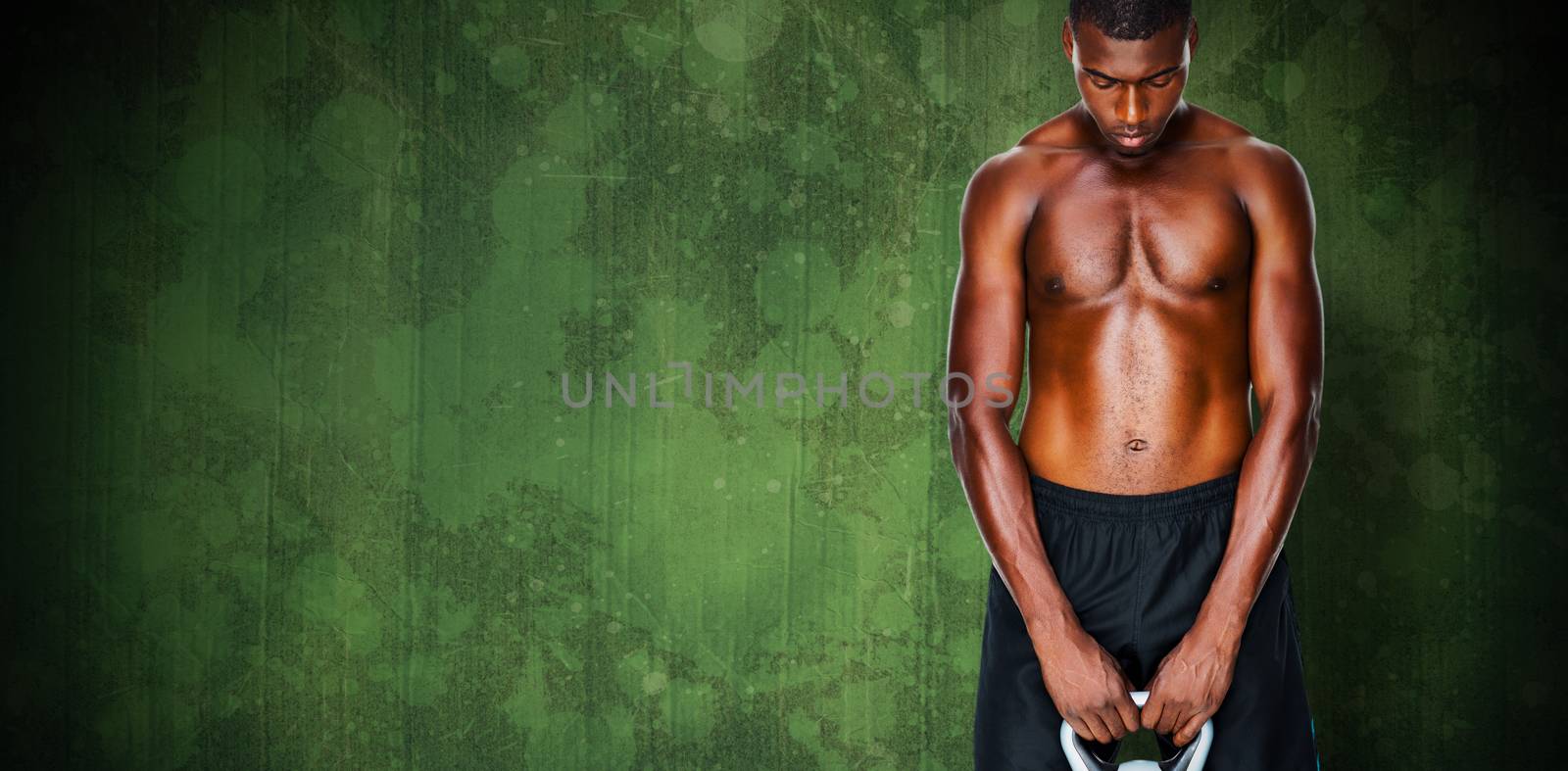 Shirtless fit young man lifting kettle bell against green paint splashed surface