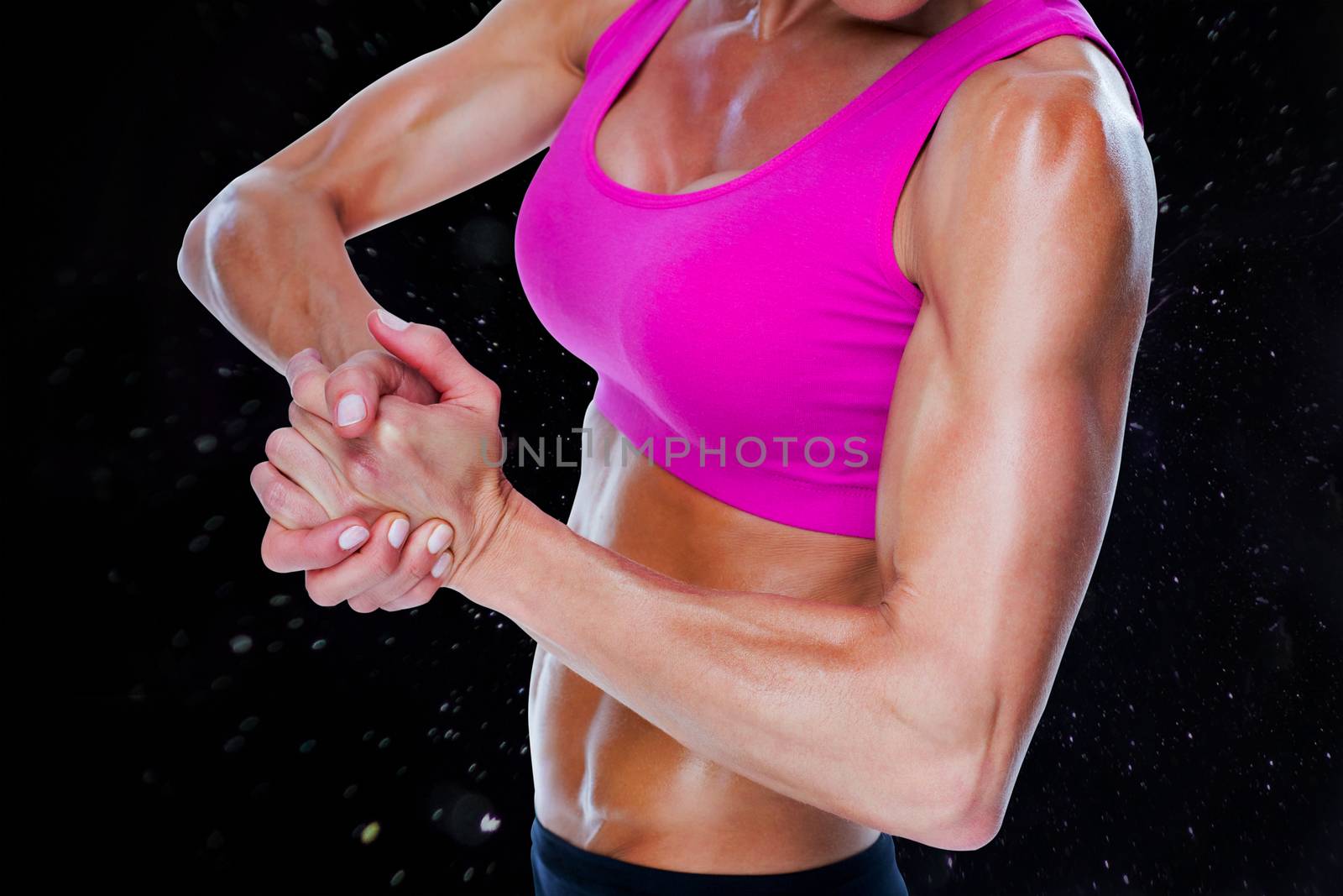 Female bodybuilder flexing mid section against black background