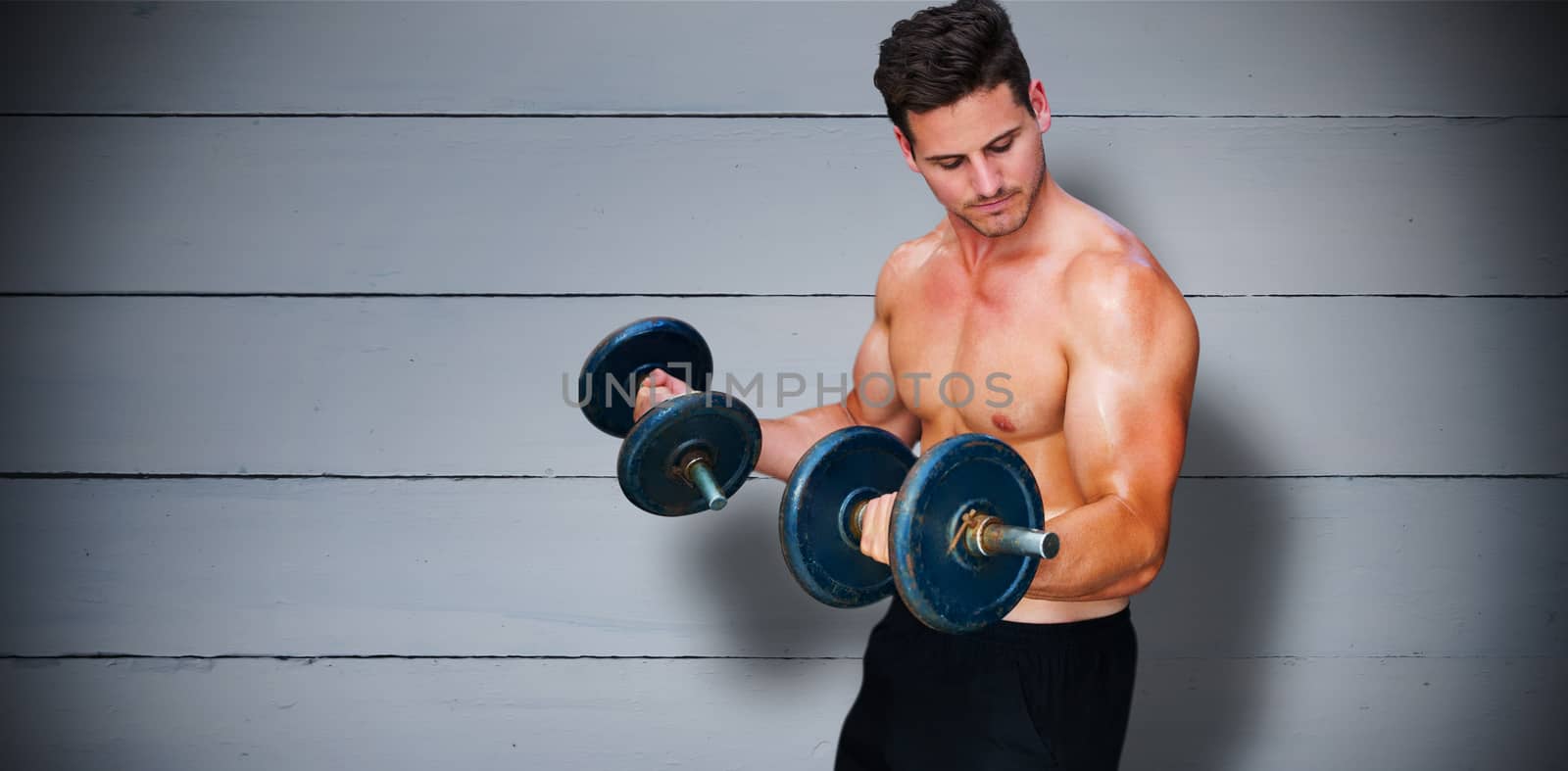 Bodybuilder lifting dumbbell against painted blue wooden planks