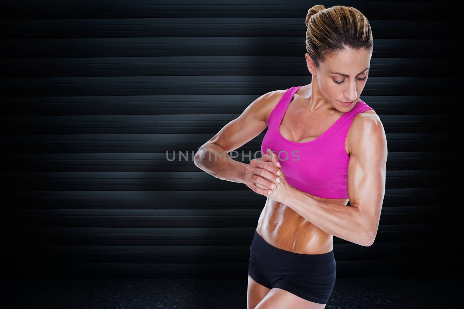 Female bodybuilder flexing with hands together against black background