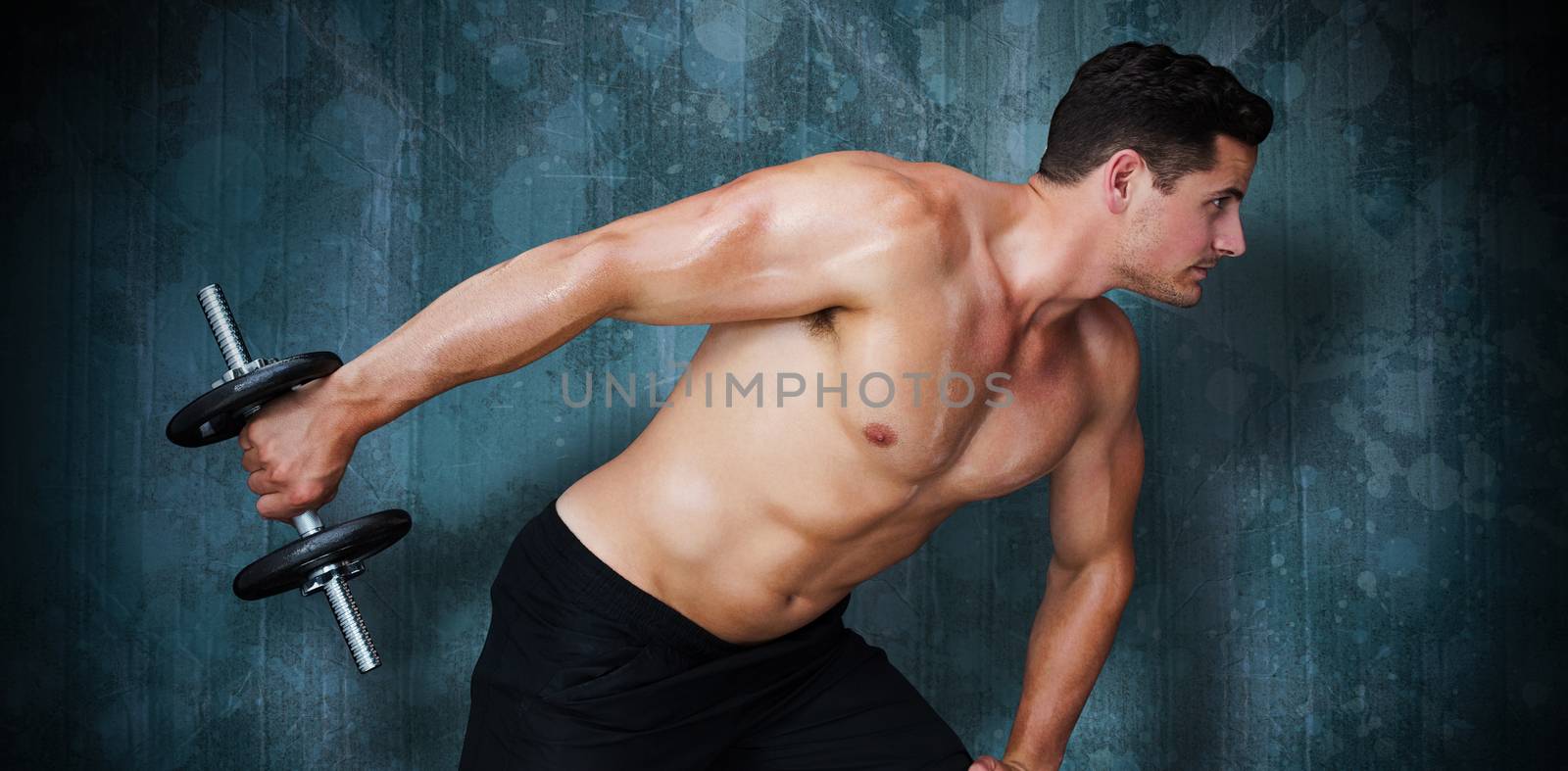 Bodybuilder lifting dumbbell against blue paint splashed surface