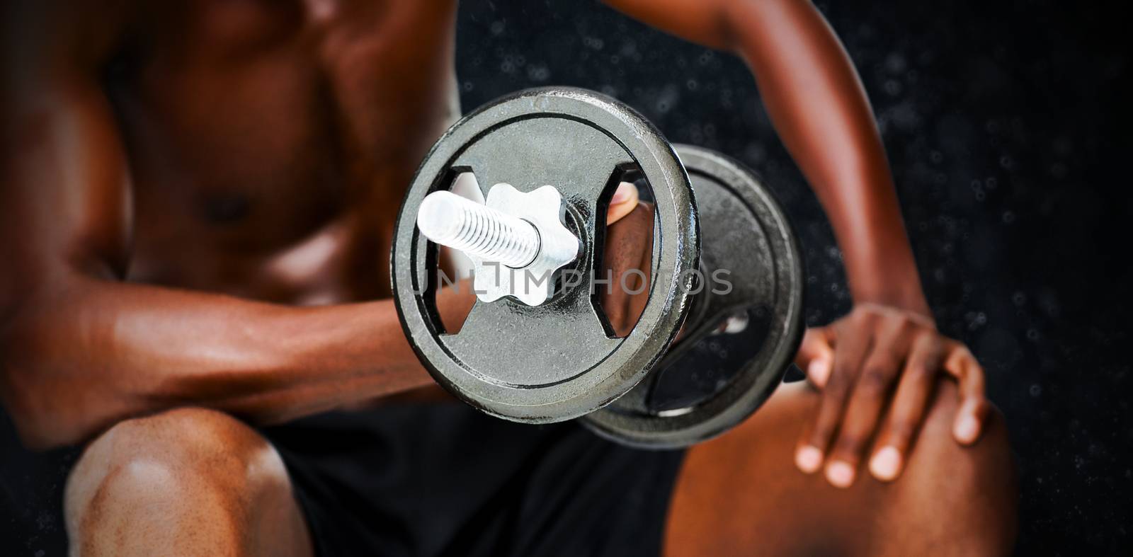 Mid section of fit shirtless man lifting dumbbell against black background